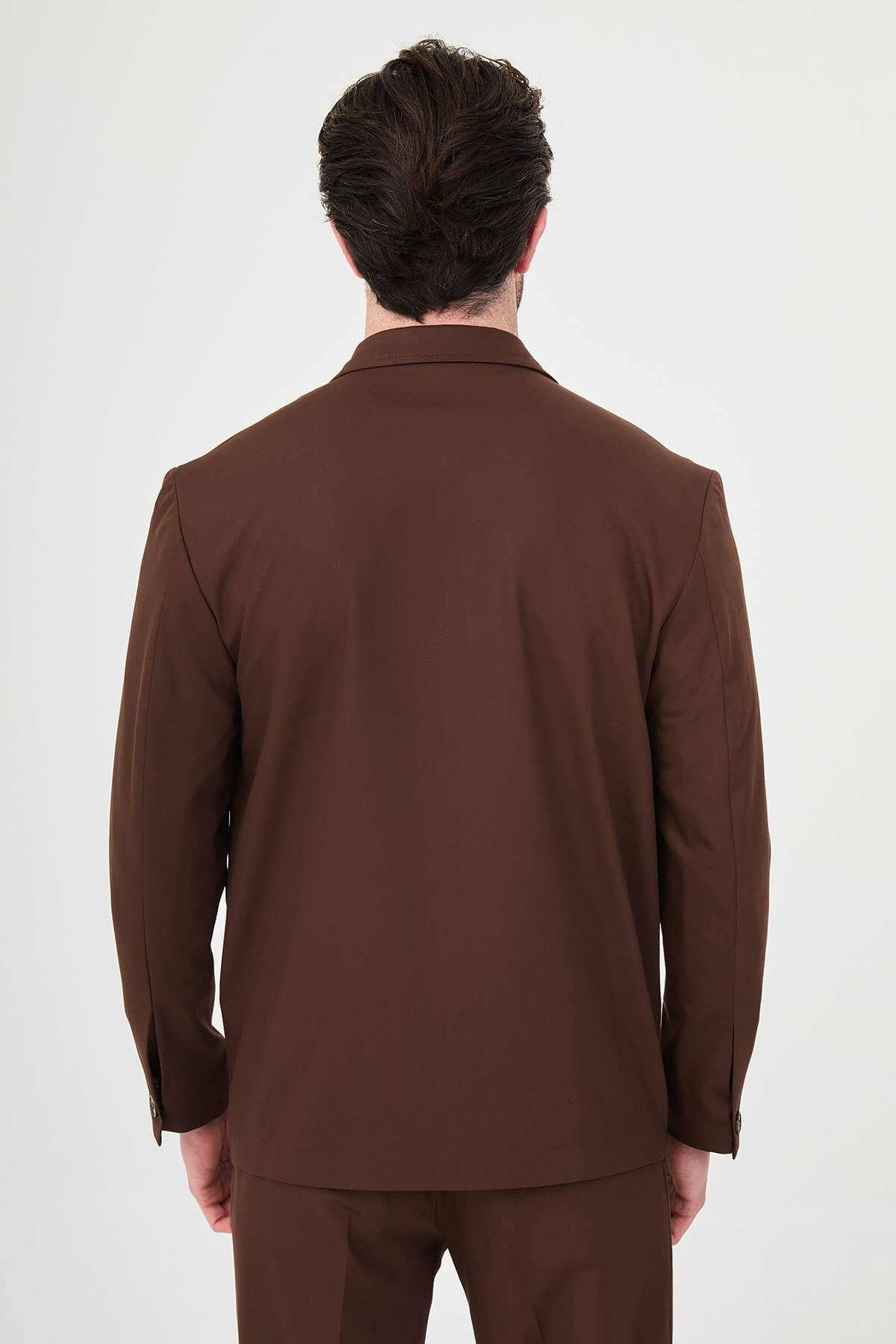 Men wearing a light brown slim fit suit with matching trousers, styled with a white crew-neck shirt, standing outdoors, showcasing a modern formal and smart-casual look.