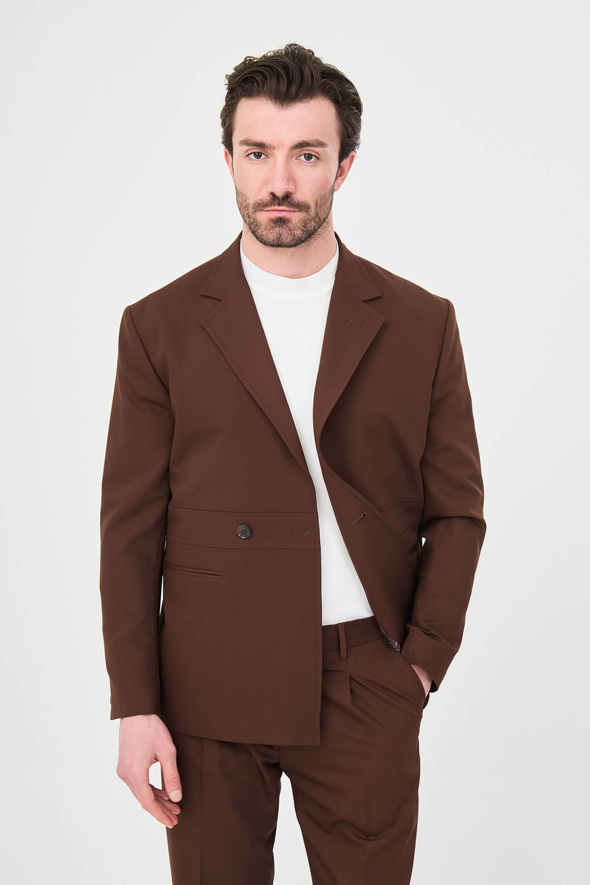 Men wearing a light brown slim fit suit with matching trousers, styled with a white crew-neck shirt, standing outdoors, showcasing a modern formal and smart-casual look.