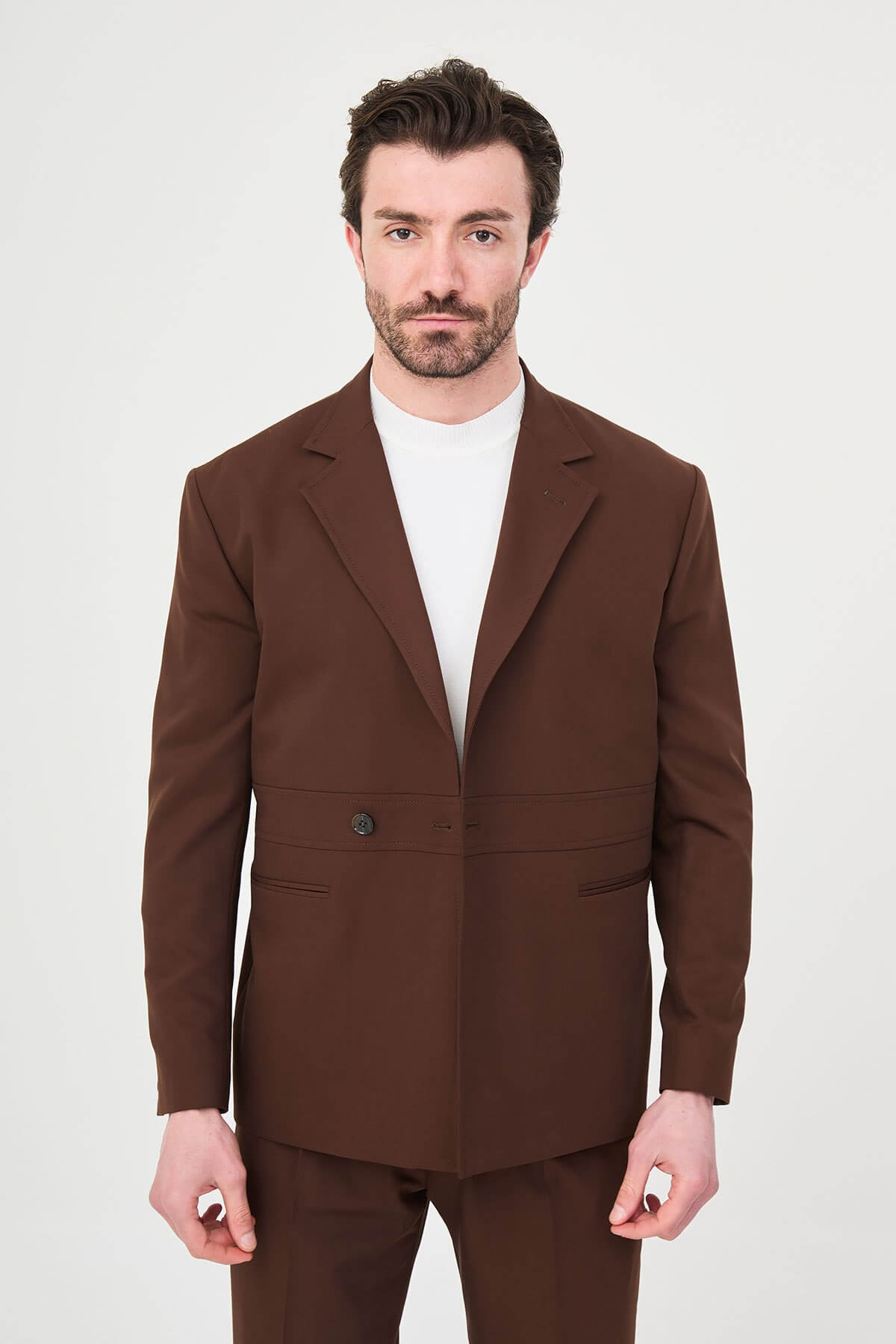 Men wearing a light brown slim fit suit with matching trousers, styled with a white crew-neck shirt, standing outdoors, showcasing a modern formal and smart-casual look.