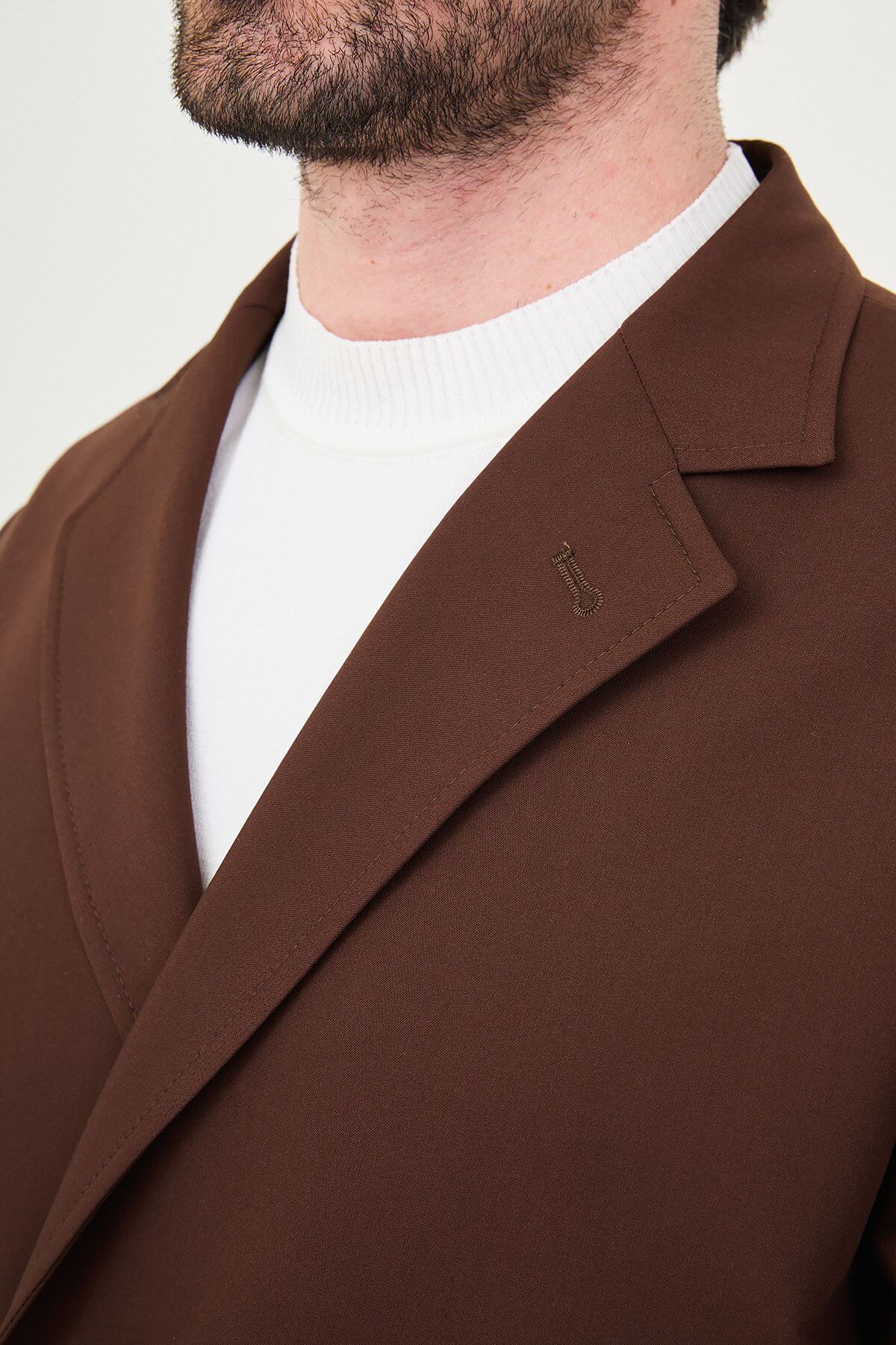 Men wearing a light brown slim fit suit with matching trousers, styled with a white crew-neck shirt, standing outdoors, showcasing a modern formal and smart-casual look.