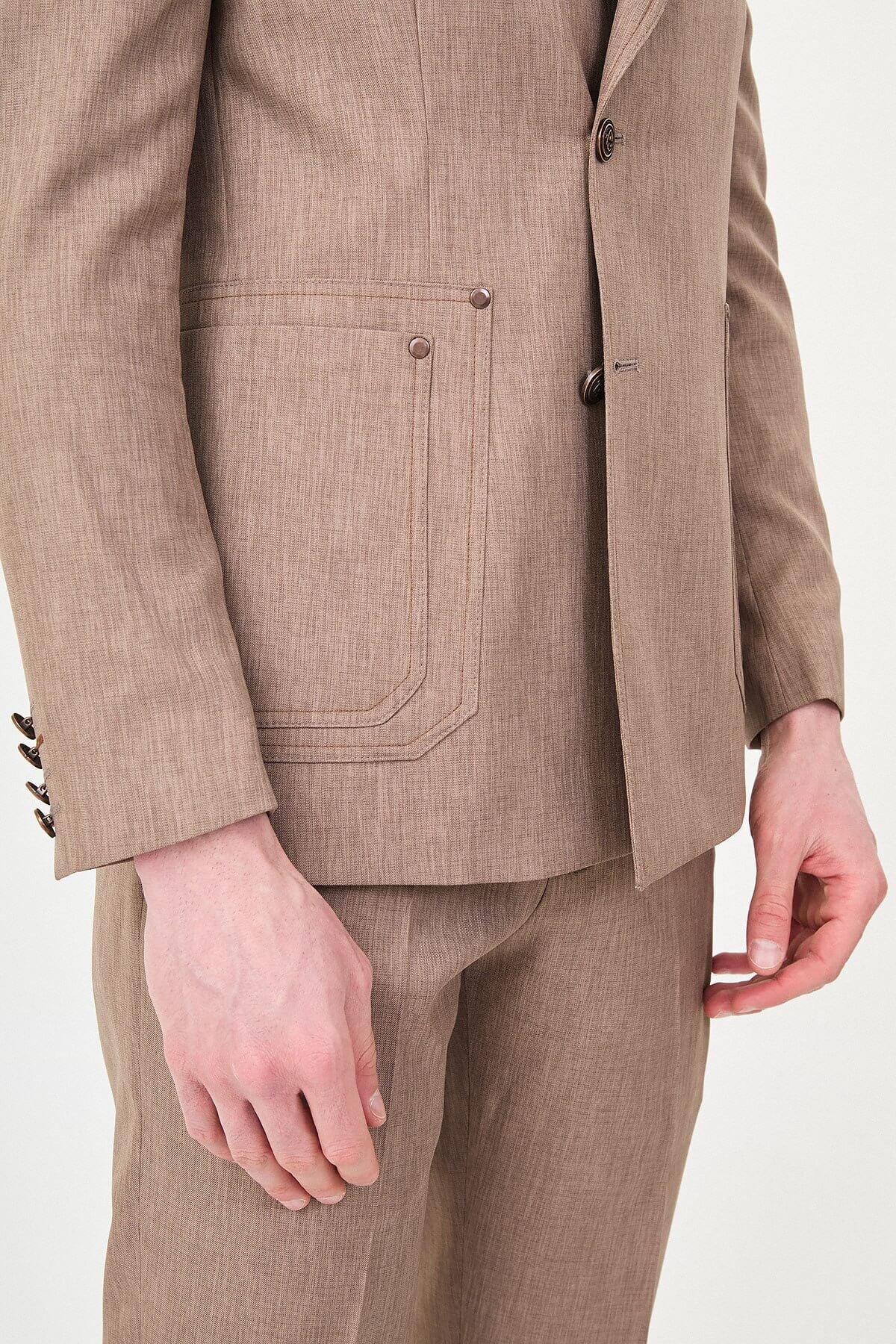 Model wearing a light brown slim-fit two-piece wedding suit with a white dress shirt, brown patterned tie, tailored trousers, and dark brown Derby shoes.