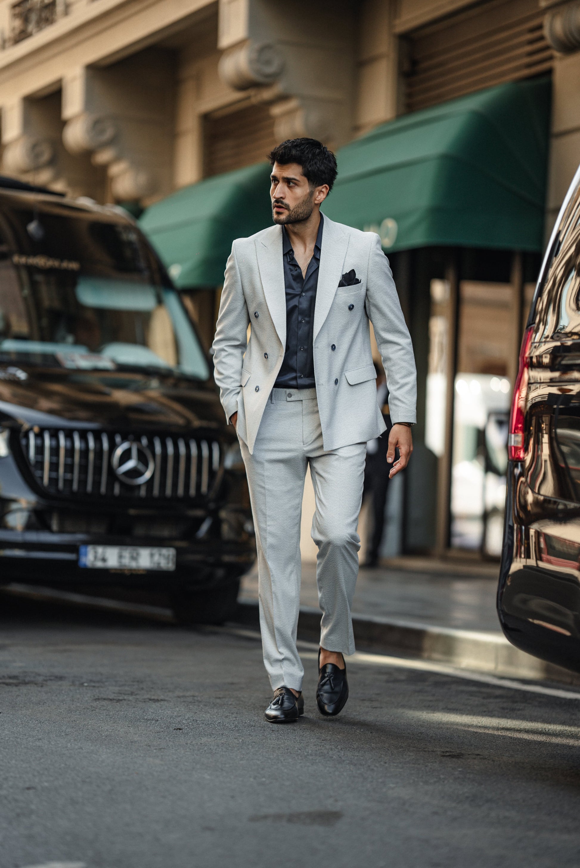 Man wearing the Cannes Light Grey Double-Breasted Suit, styled with a white shirt and loafers, walking confidently on the streets in an urban setting.