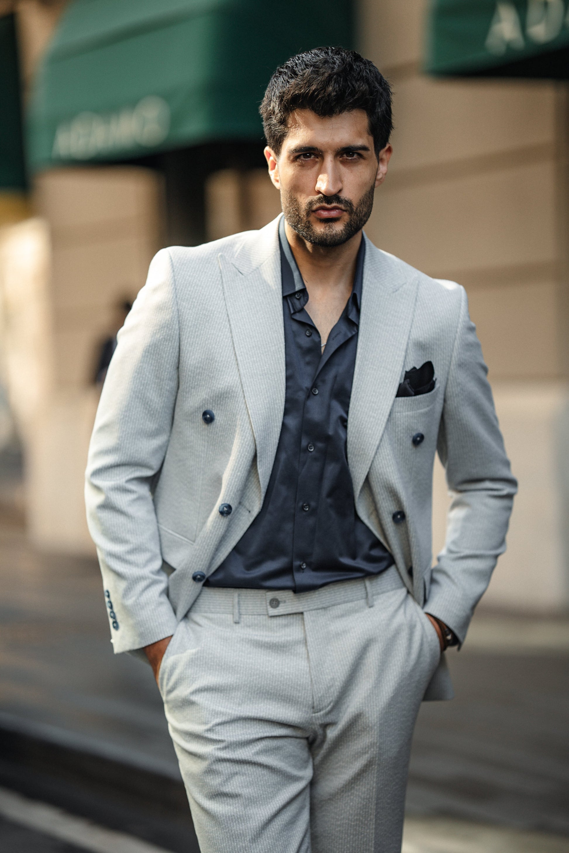 Man wearing the Cannes Light Grey Double-Breasted Suit, styled with a white shirt and loafers, walking confidently on the streets in an urban setting.