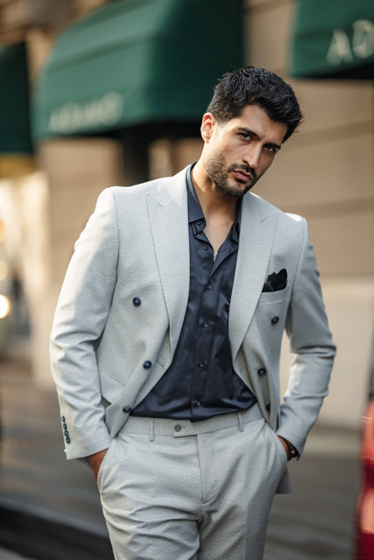 Man wearing the Cannes Light Grey Double-Breasted Suit, styled with a white shirt and loafers, walking confidently on the streets in an urban setting.