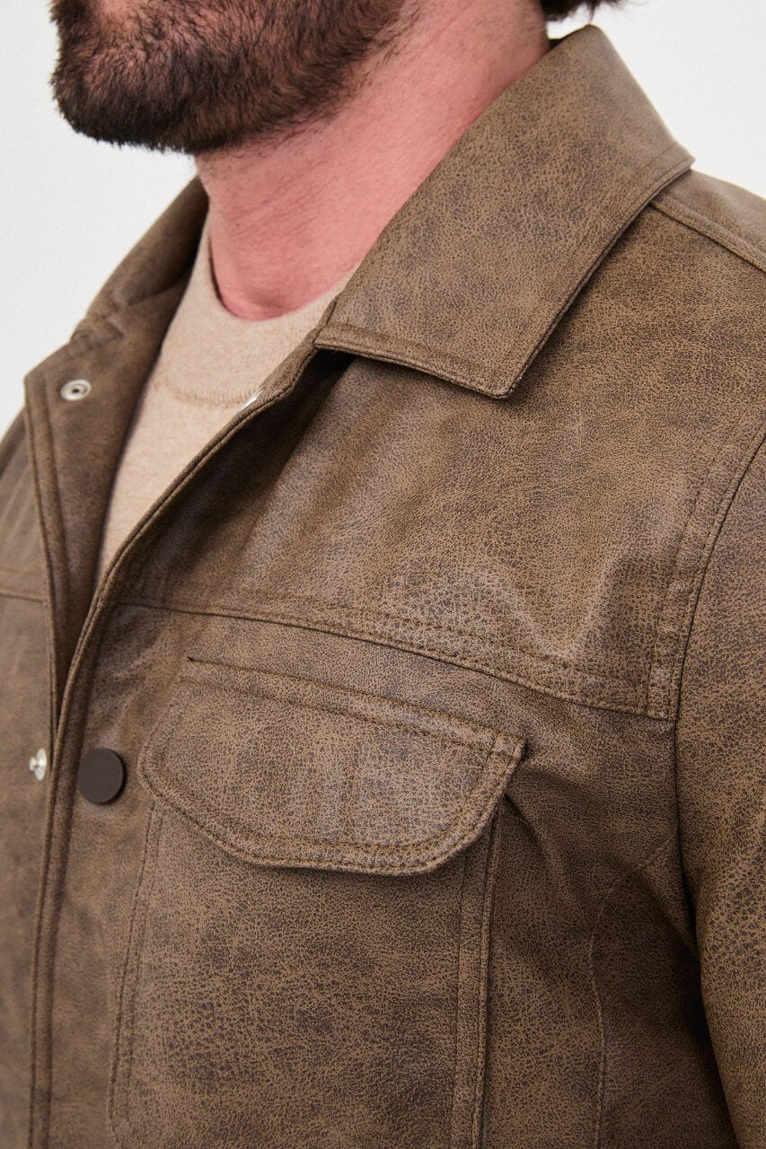 Men's mink-brown PU leather jacket styled with dark jeans, a beige sweater and brown boots.