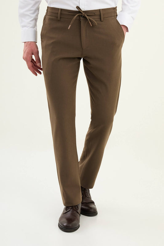 Men wearing mink slim-fit drawstring trousers with elastic waistband, styled with sneakers and dress shoes for versatile summer menswear.