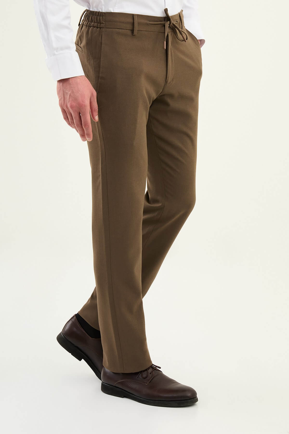 Men wearing mink slim-fit drawstring trousers with elastic waistband, styled with sneakers and dress shoes for versatile summer menswear.