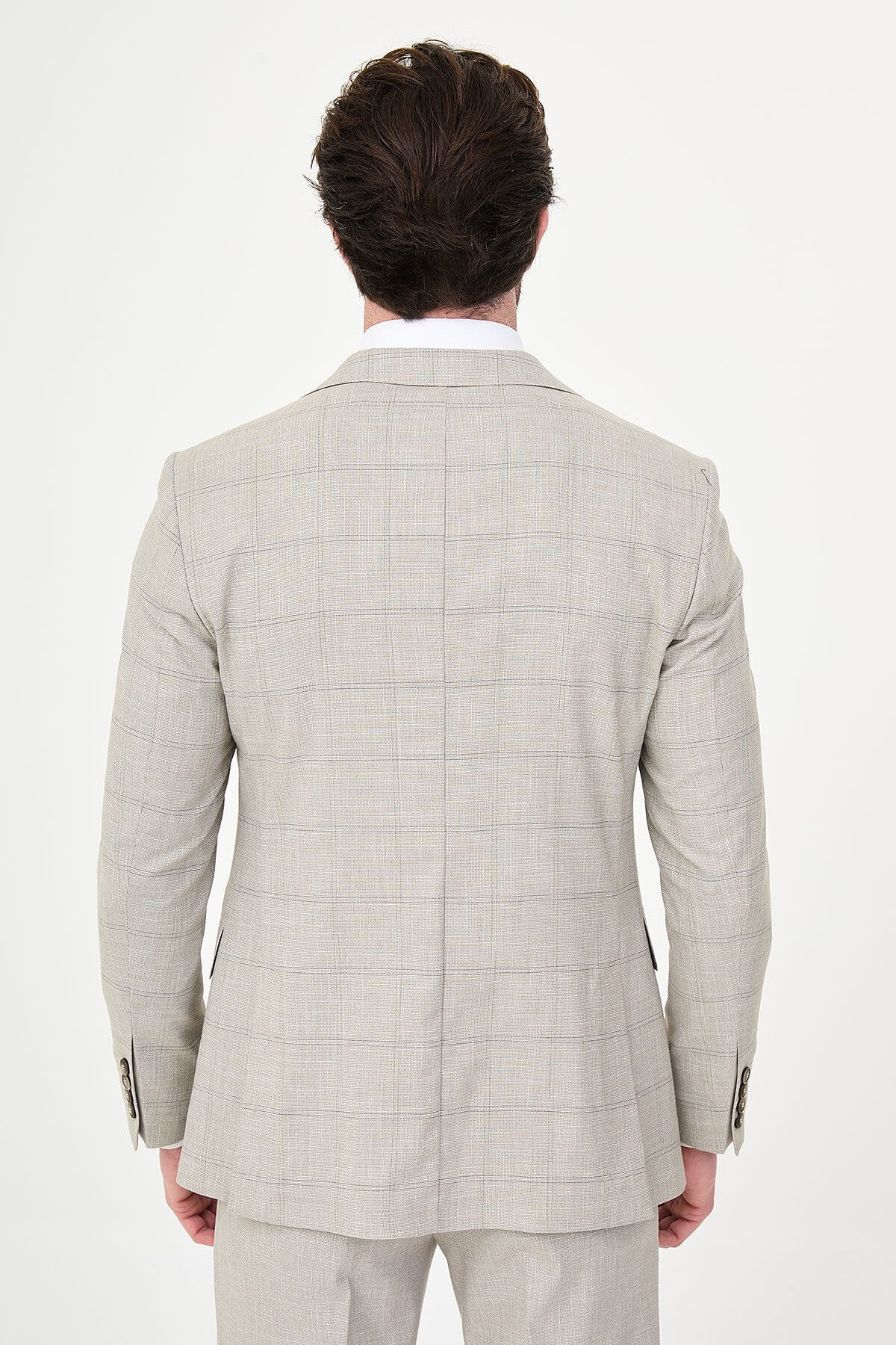 a mink slim-fit three-piece suit with a fine windowpane check, matching waistcoat and trousers, white dress shirt, patterned navy and brown tie, and dark brown leather shoes.
