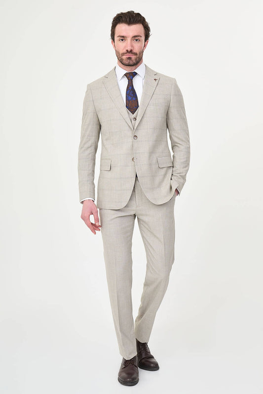 a mink slim-fit three-piece suit with a fine windowpane check, matching waistcoat and trousers, white dress shirt, patterned navy and brown tie, and dark brown leather shoes.