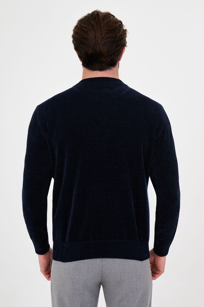 Men’s navy blue crew neck knit sweater in a cotton blend slim fit design styled with grey trousers for a refined fall winter outfit.
