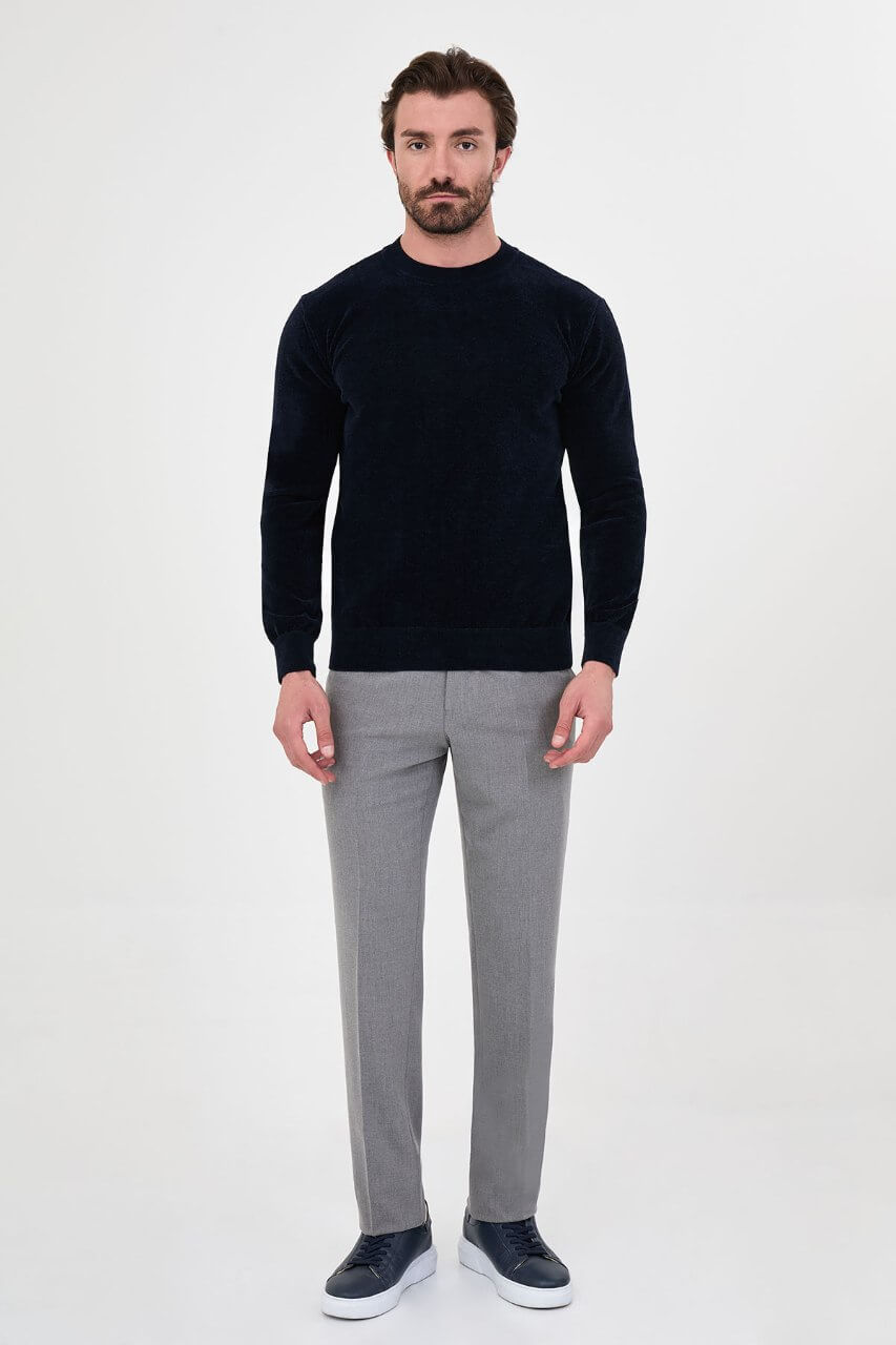 Men’s navy blue crew neck knit sweater in a cotton blend slim fit design styled with grey trousers for a refined fall winter outfit.
