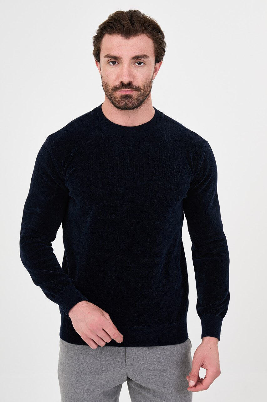 Men’s navy blue crew neck knit sweater in a cotton blend slim fit design styled with grey trousers for a refined fall winter outfit.