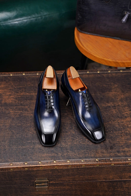 Men’s navy blue leather Oxford dress shoes with polished finish, lace-up design, sleek pointed toe, and elegant formal silhouette.