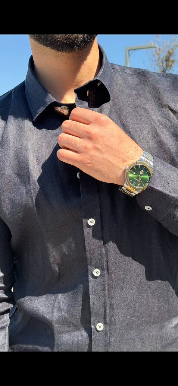 Man wearing a navy blue linen collared shirt, standing by the waterfront with sunglasses, casual summer outfit.