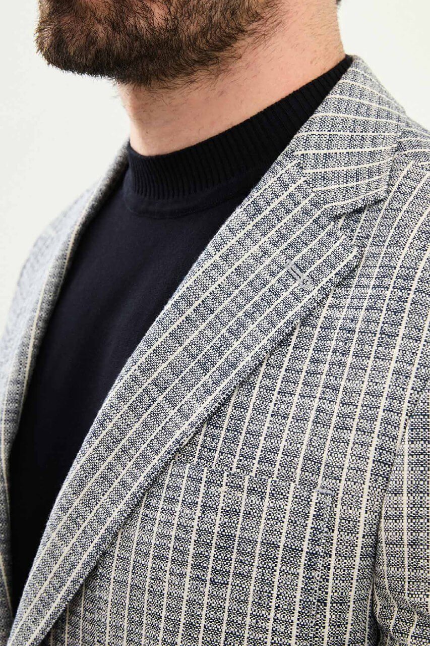 Men’s navy blue slim fit cotton linen blazer with a lightweight textured finish, styled with white trousers for smart casual summer elegance.