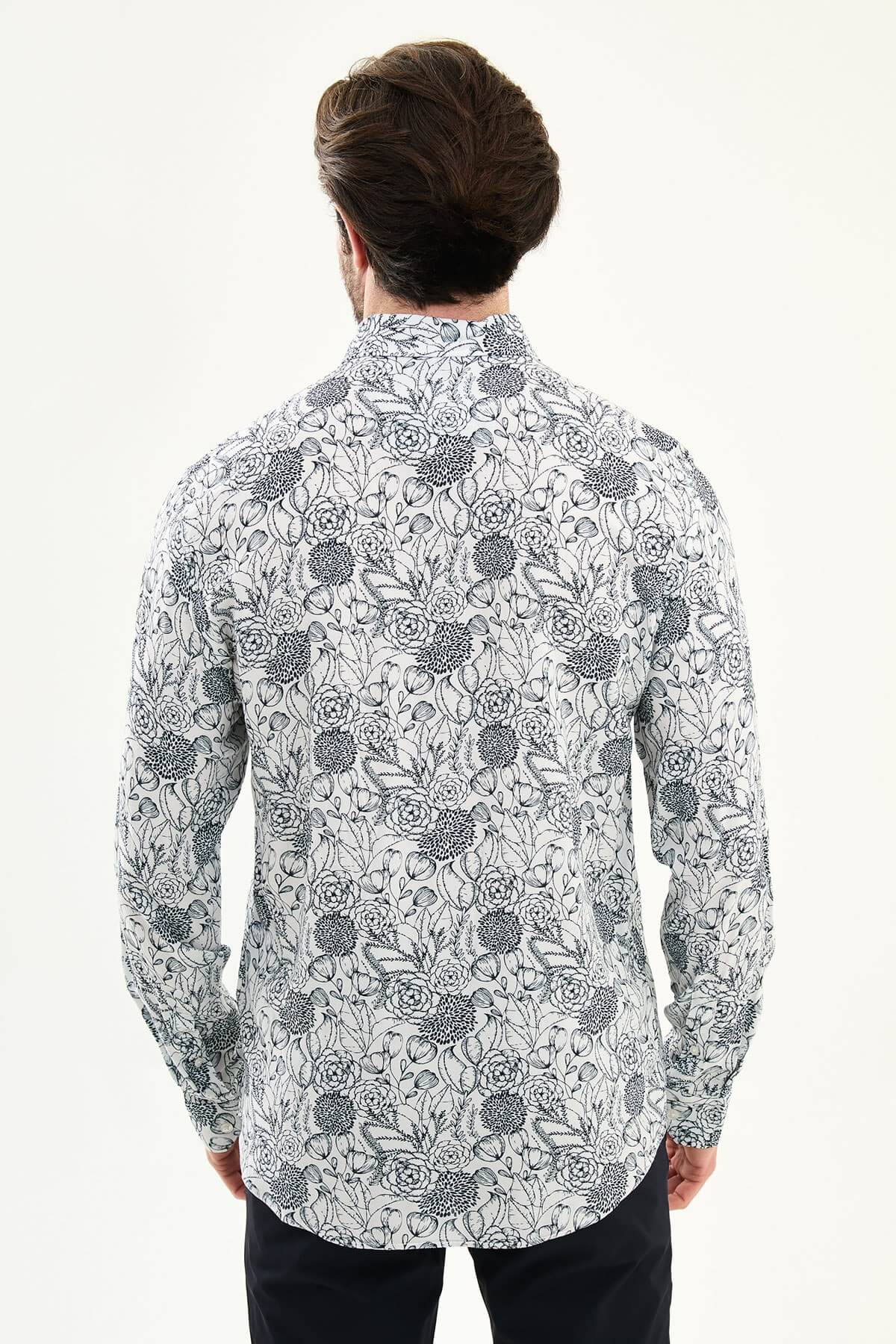 Man wearing a navy blue patterned slim-fit long sleeve shirt, standing front-facing, styled with dark trousers.