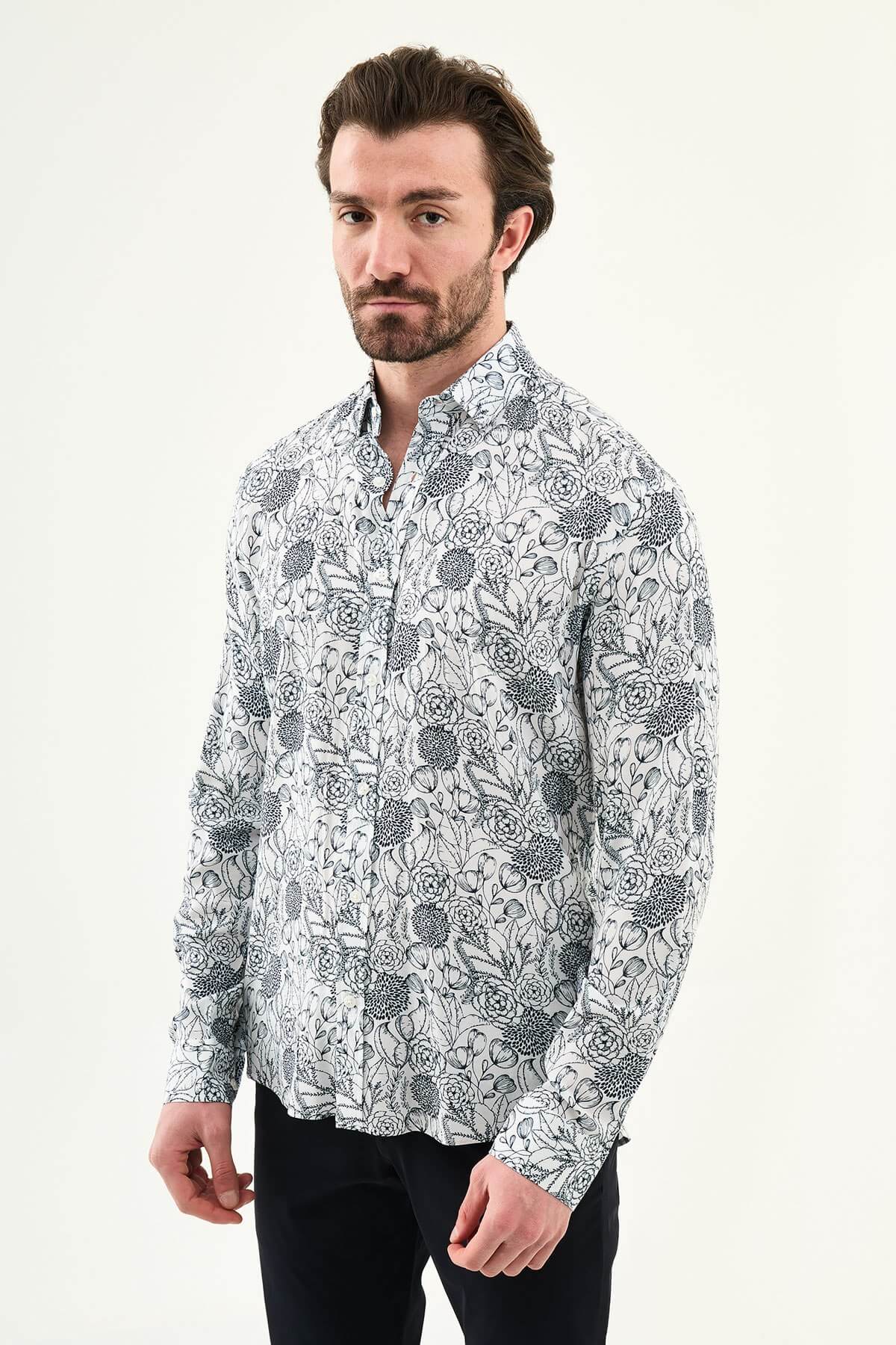 Man wearing a navy blue patterned slim-fit long sleeve shirt, standing front-facing, styled with dark trousers.