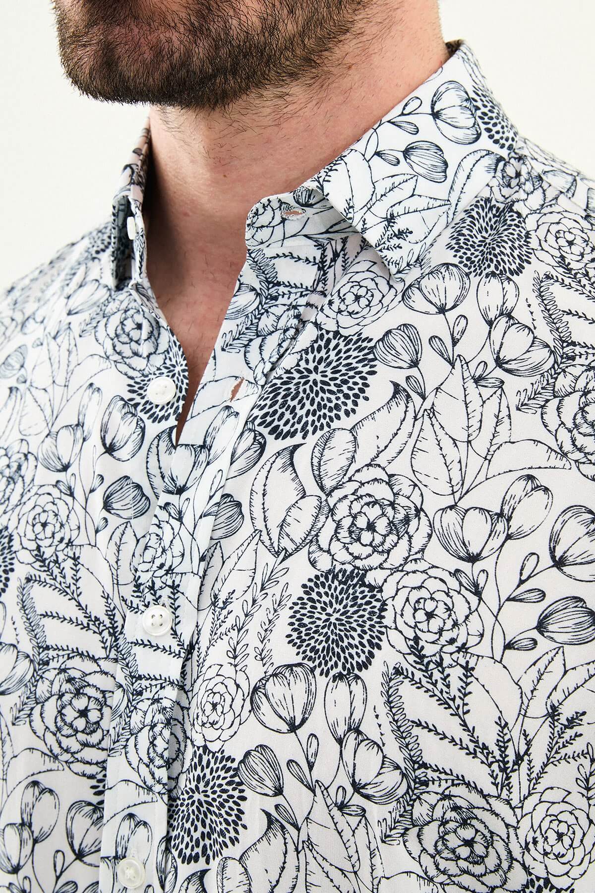 Man wearing a navy blue patterned slim-fit long sleeve shirt, standing front-facing, styled with dark trousers.