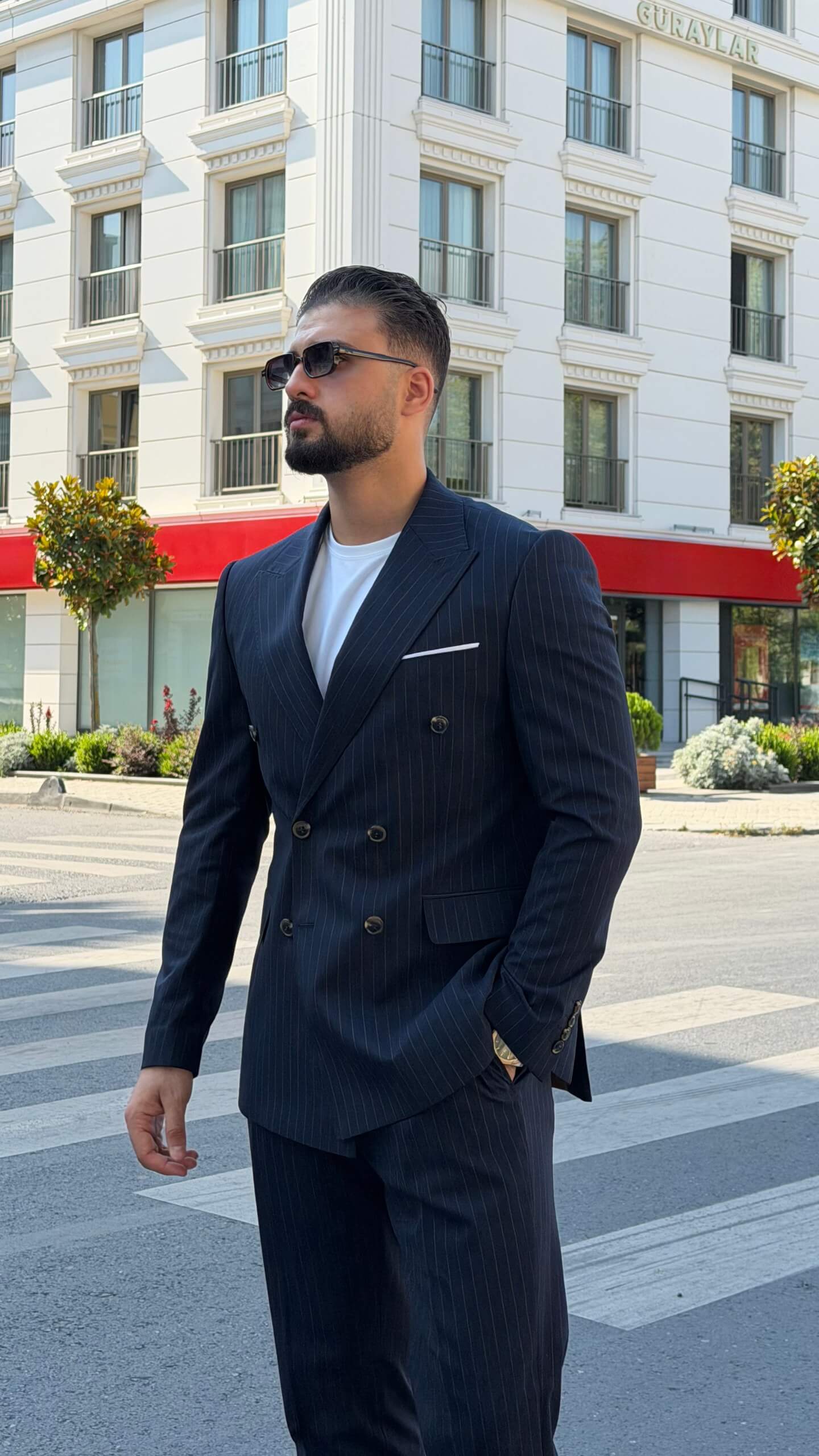 Men’s navy blue pinstripe double-breasted wool suit styled with white T-shirt and sneakers