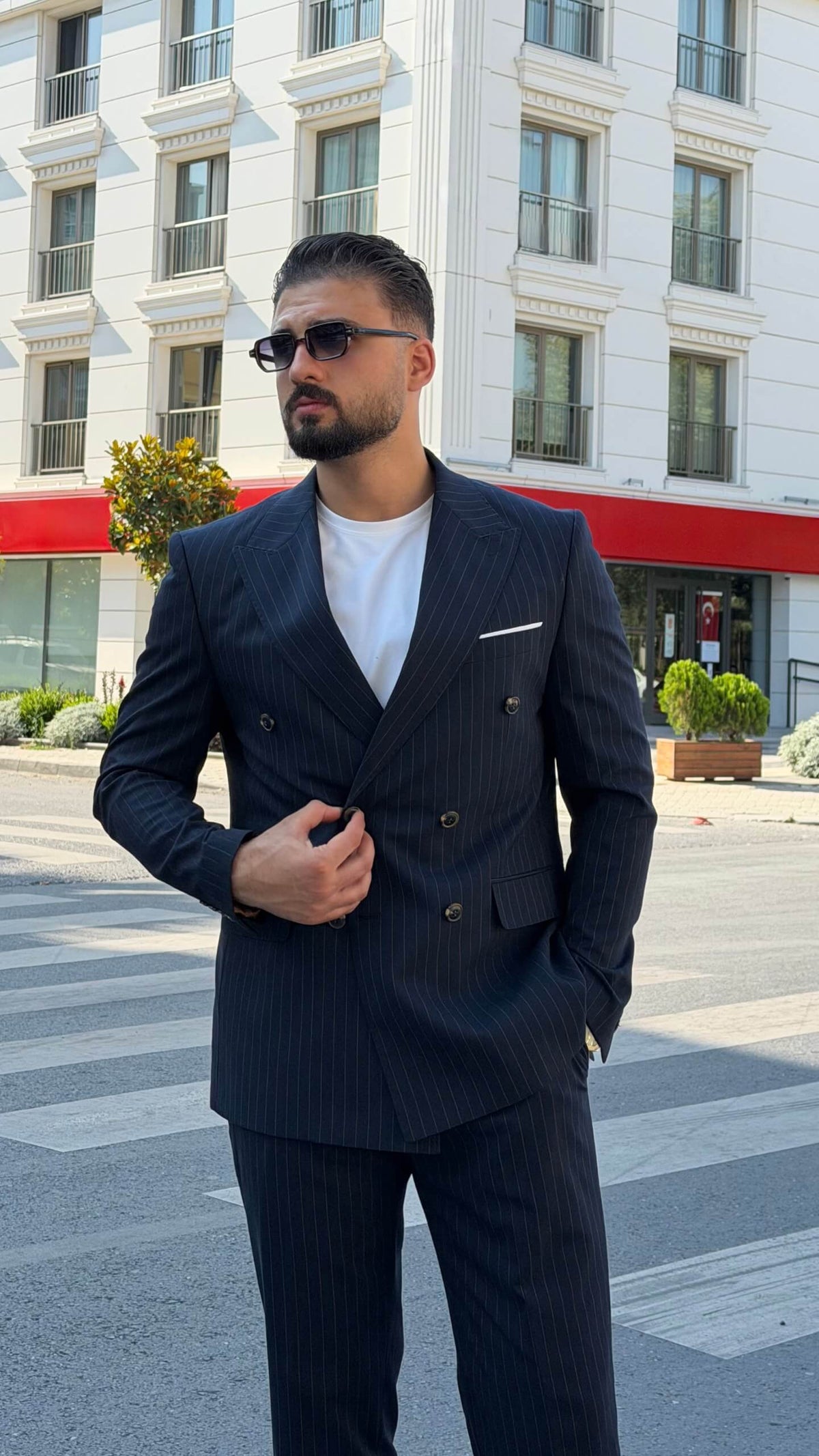 Men’s navy blue pinstripe double-breasted wool suit styled with white T-shirt and sneakers