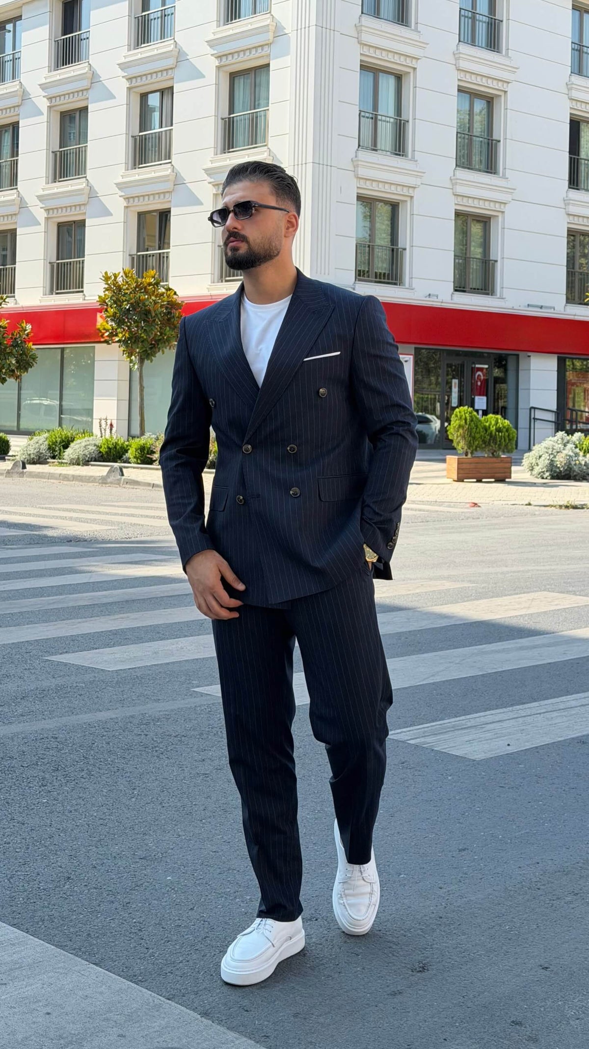 Men’s navy blue pinstripe double-breasted wool suit styled with white T-shirt and sneakers