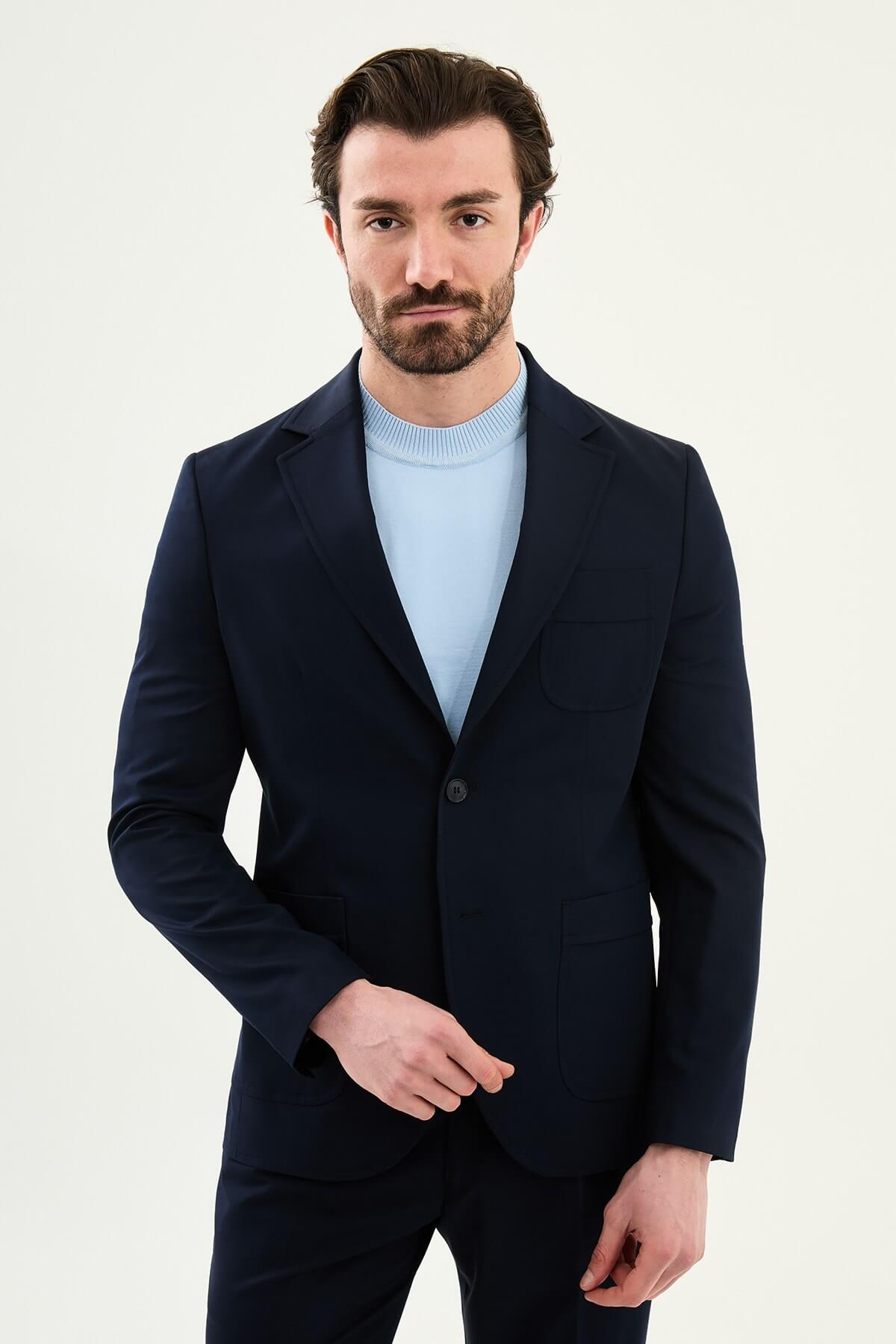 Men’s navy blue slim fit blazer with a clean modern design and stretch fabric, styled with a light blue knit top for elegant smart casual and formal occasions.