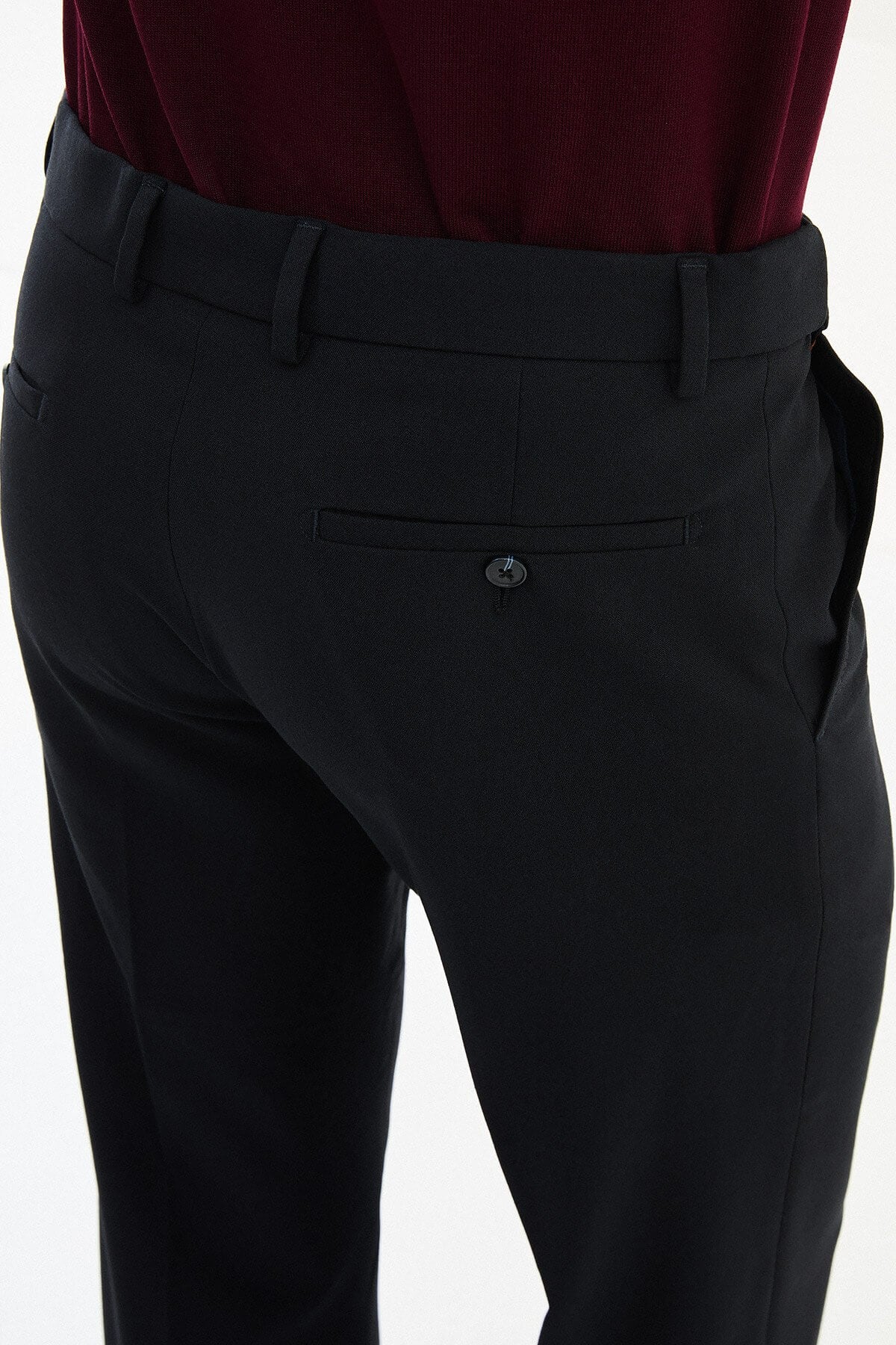 Man wearing navy slim-fit dress trousers with a tailored fit, styled with black dress shoes and a burgundy shirt.
