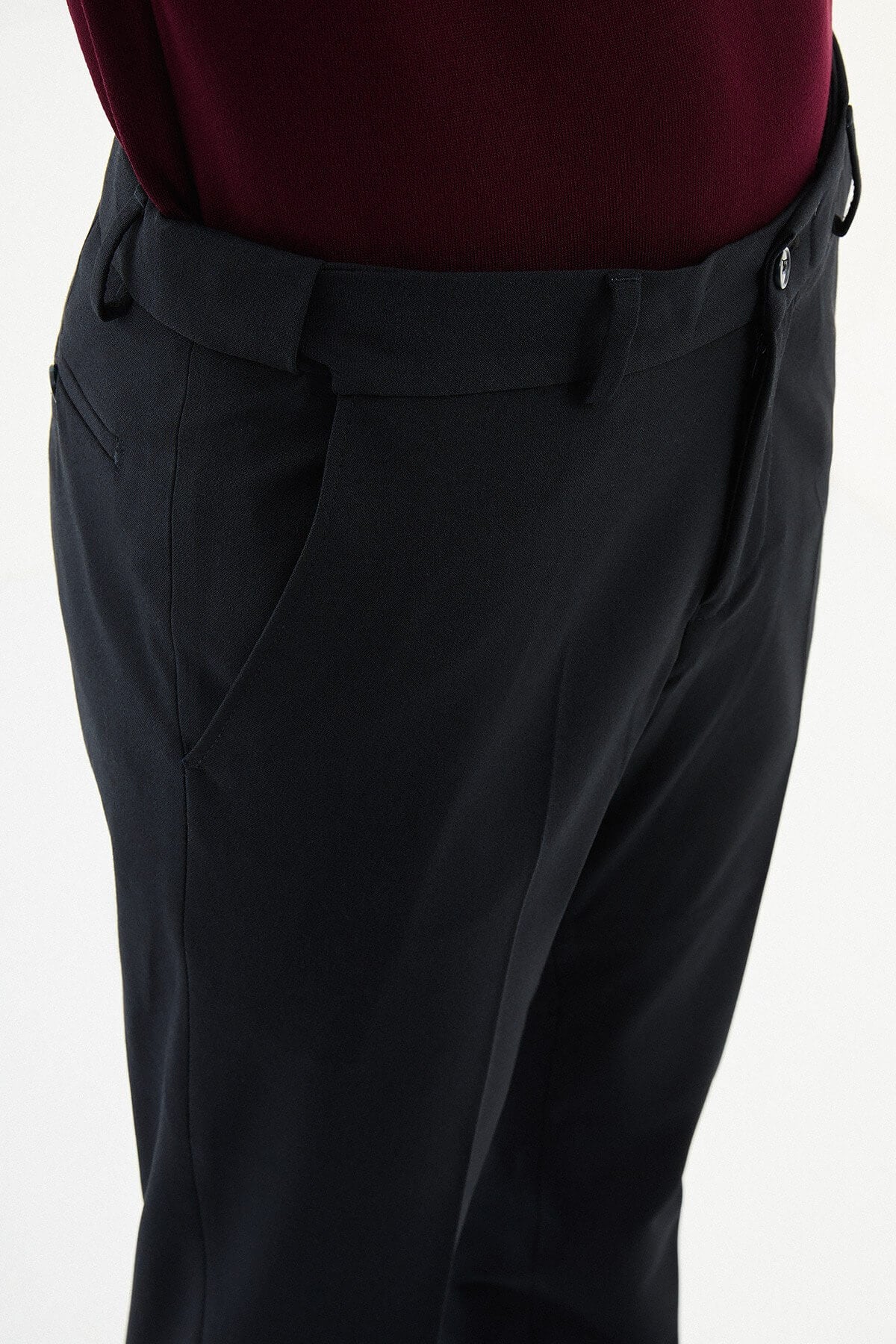 Man wearing navy slim-fit dress trousers with a tailored fit, styled with black dress shoes and a burgundy shirt.