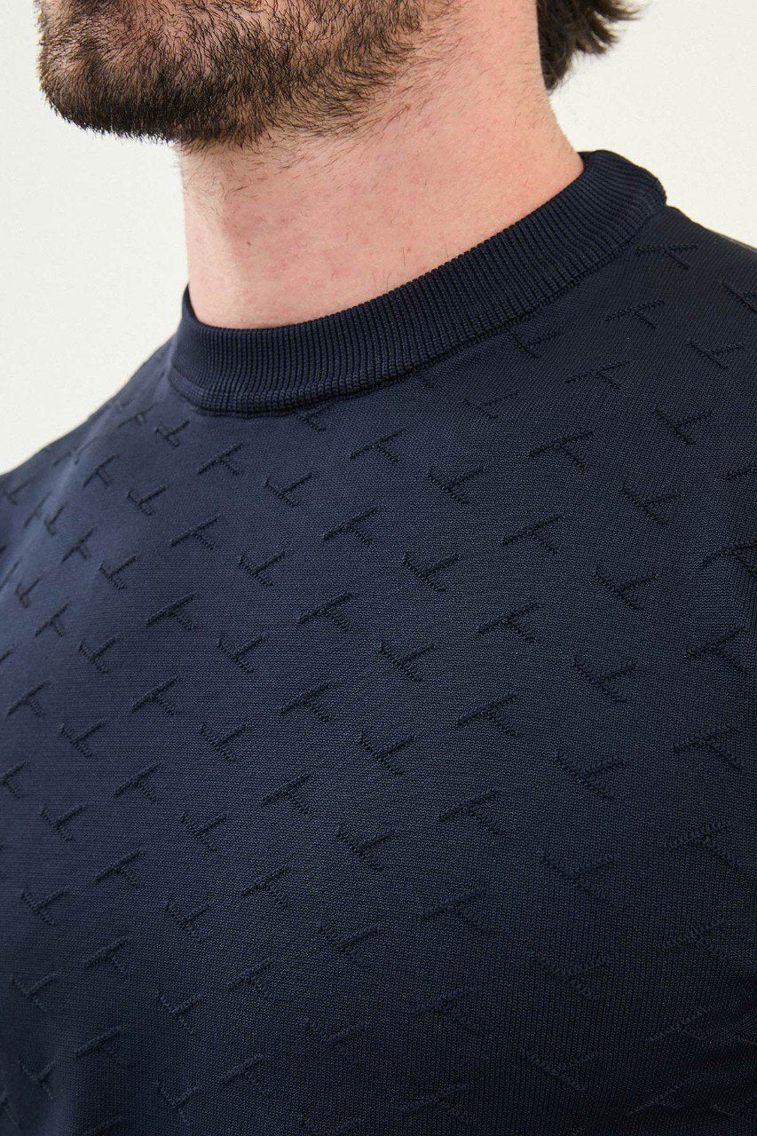 Men’s slim-fit navy blue crew-neck sweater with geometric ‘T’ textured knit front panel, cotton-viscose-elastane blend, styled with blue denim for winter smart-casual.
