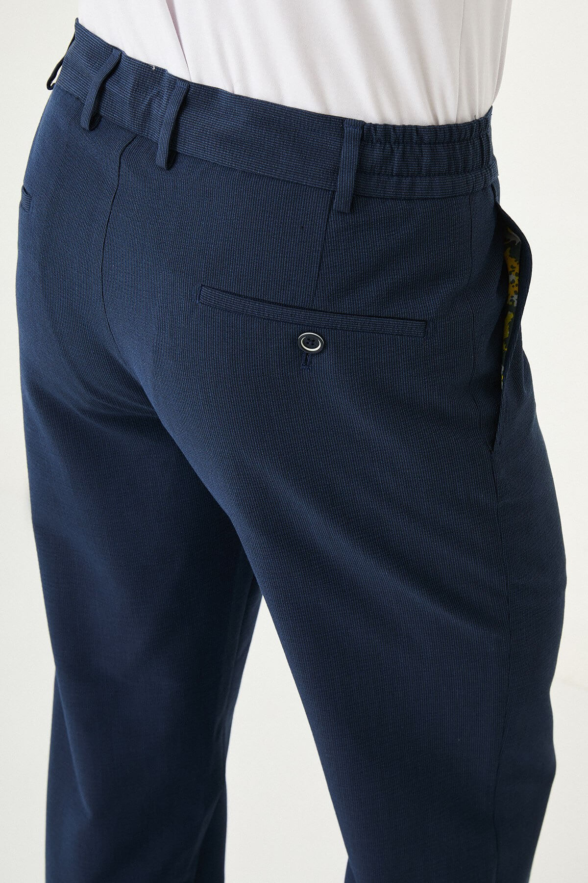 Man wearing navy blue slim-fit summer trousers paired with a white polo shirt and navy sneakers.