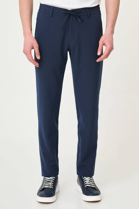 Man wearing navy blue slim-fit summer trousers paired with a white polo shirt and navy sneakers.