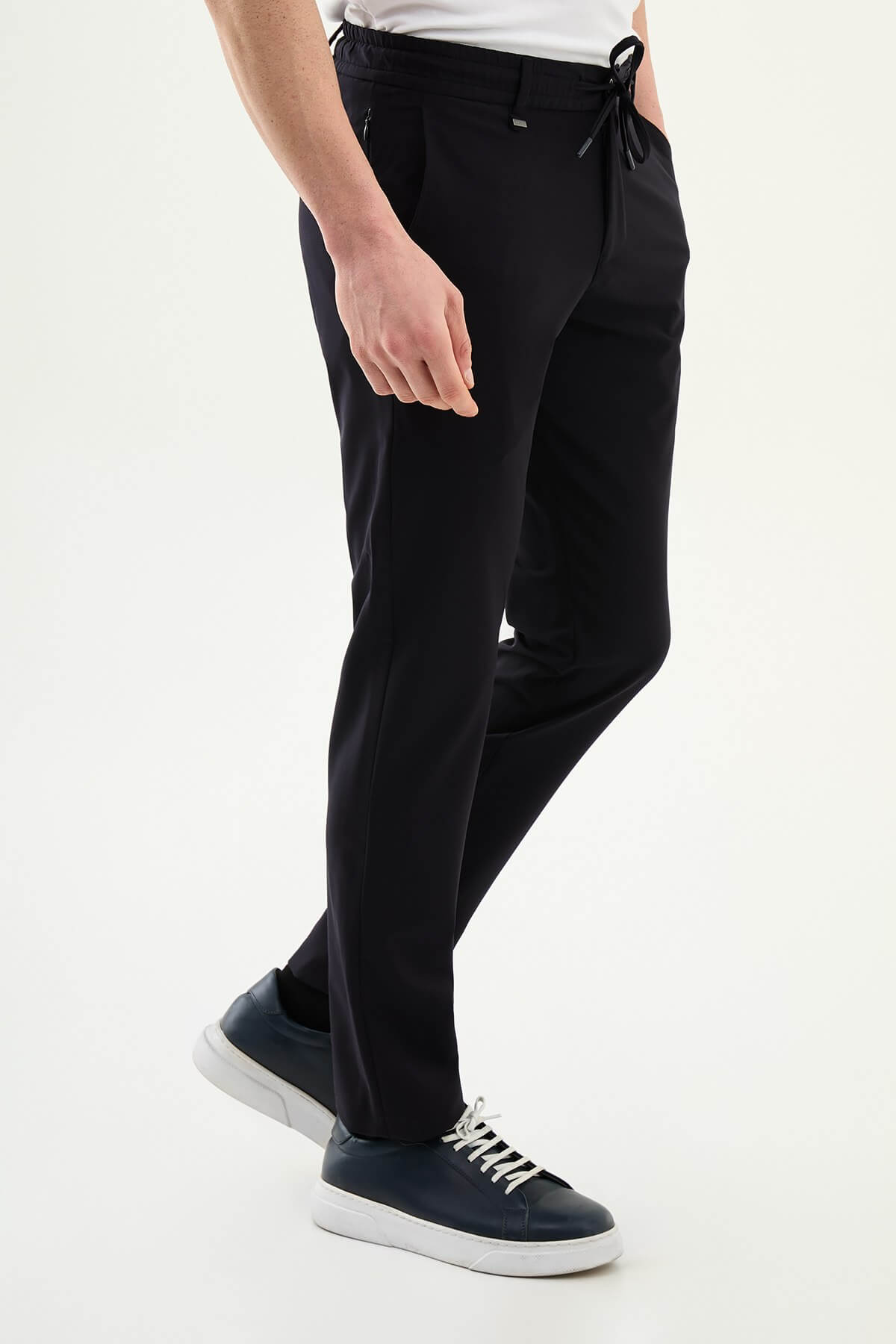 Man wearing navy blue slim-fit summer trousers styled with white sneakers and a short-sleeve summer shirt.