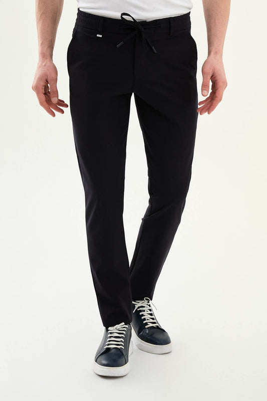 Man wearing navy blue slim-fit summer trousers styled with white sneakers and a short-sleeve summer shirt.