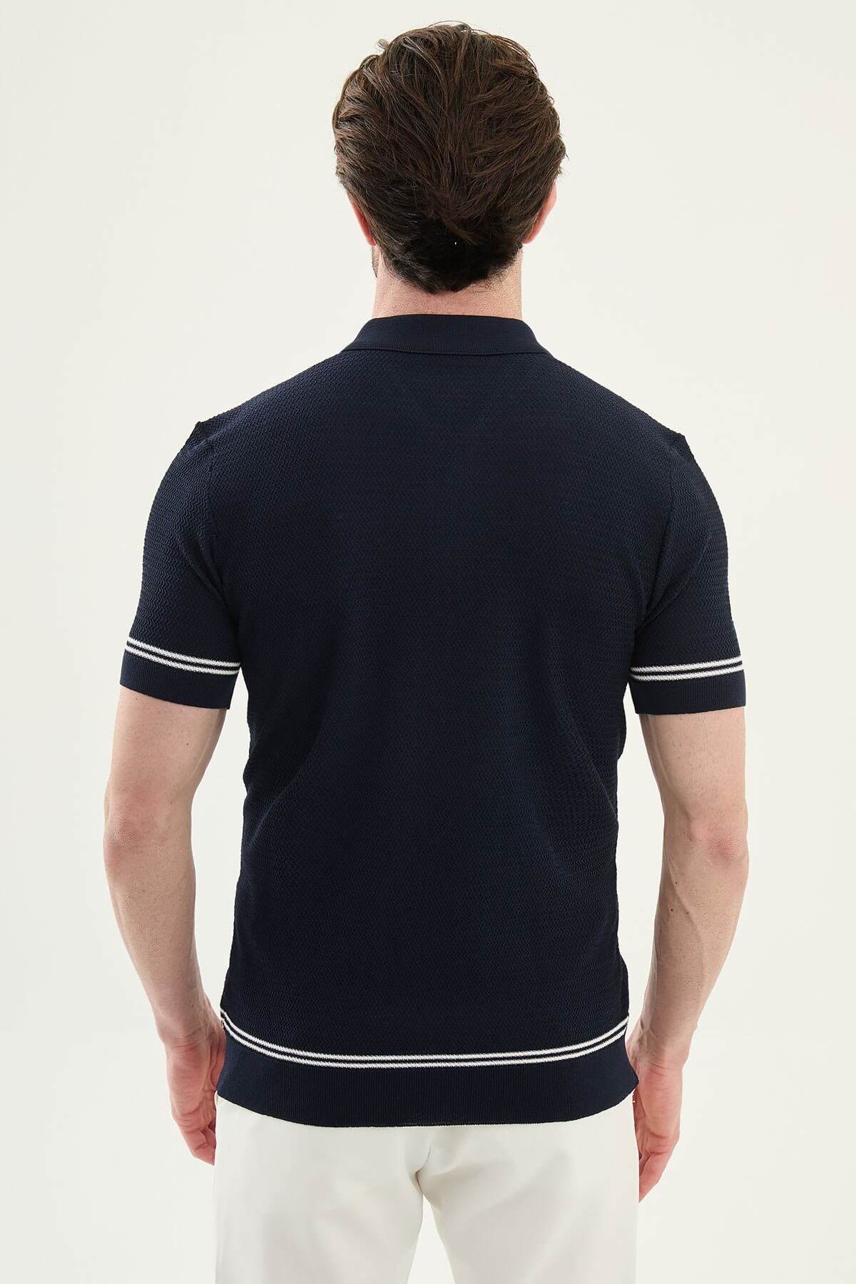 Man wearing navy blue slim-fit quarter-zip polo t-shirt with white stripe accents, paired with white trousers.
