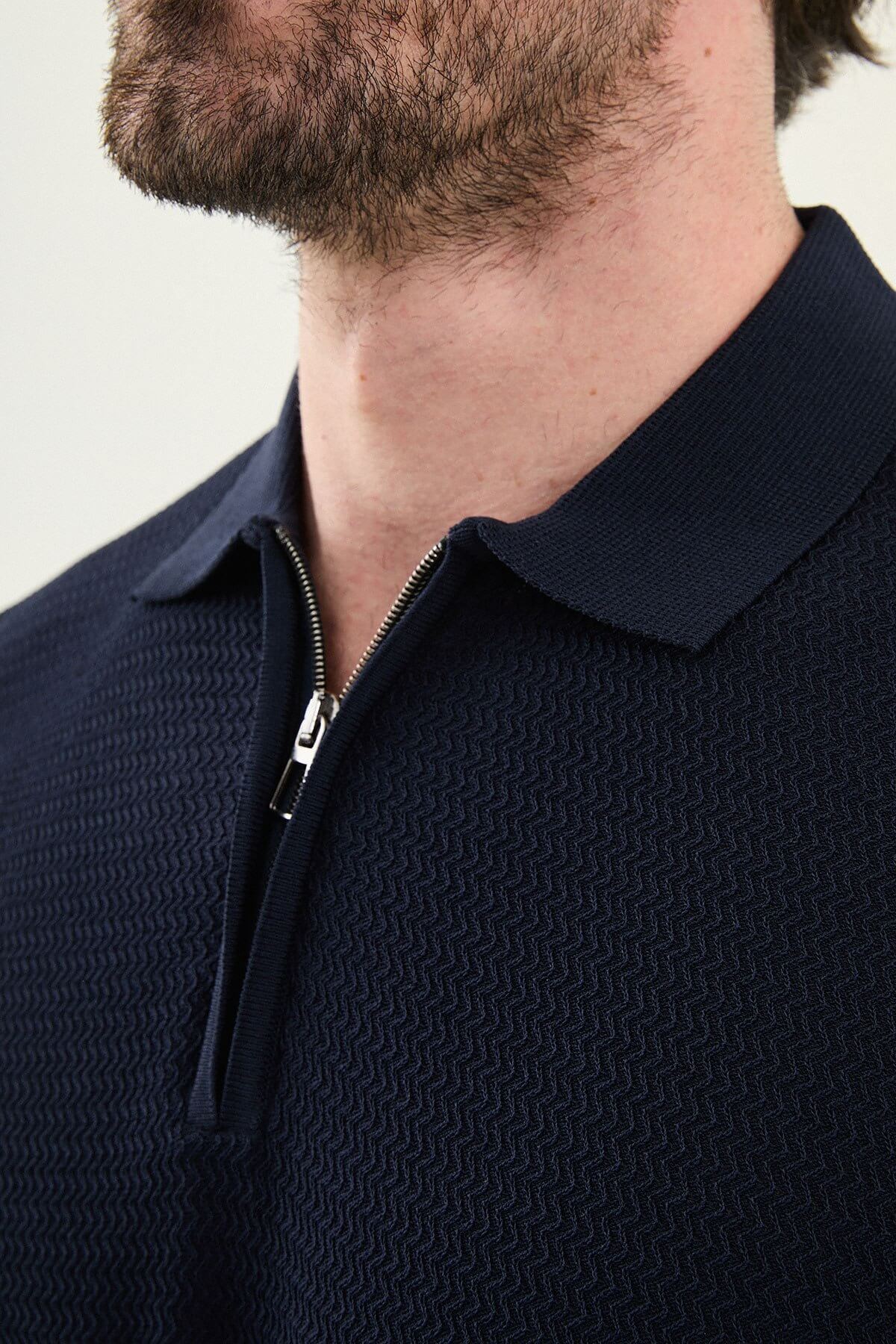 Man wearing navy blue slim-fit quarter-zip polo t-shirt with white stripe accents, paired with white trousers.