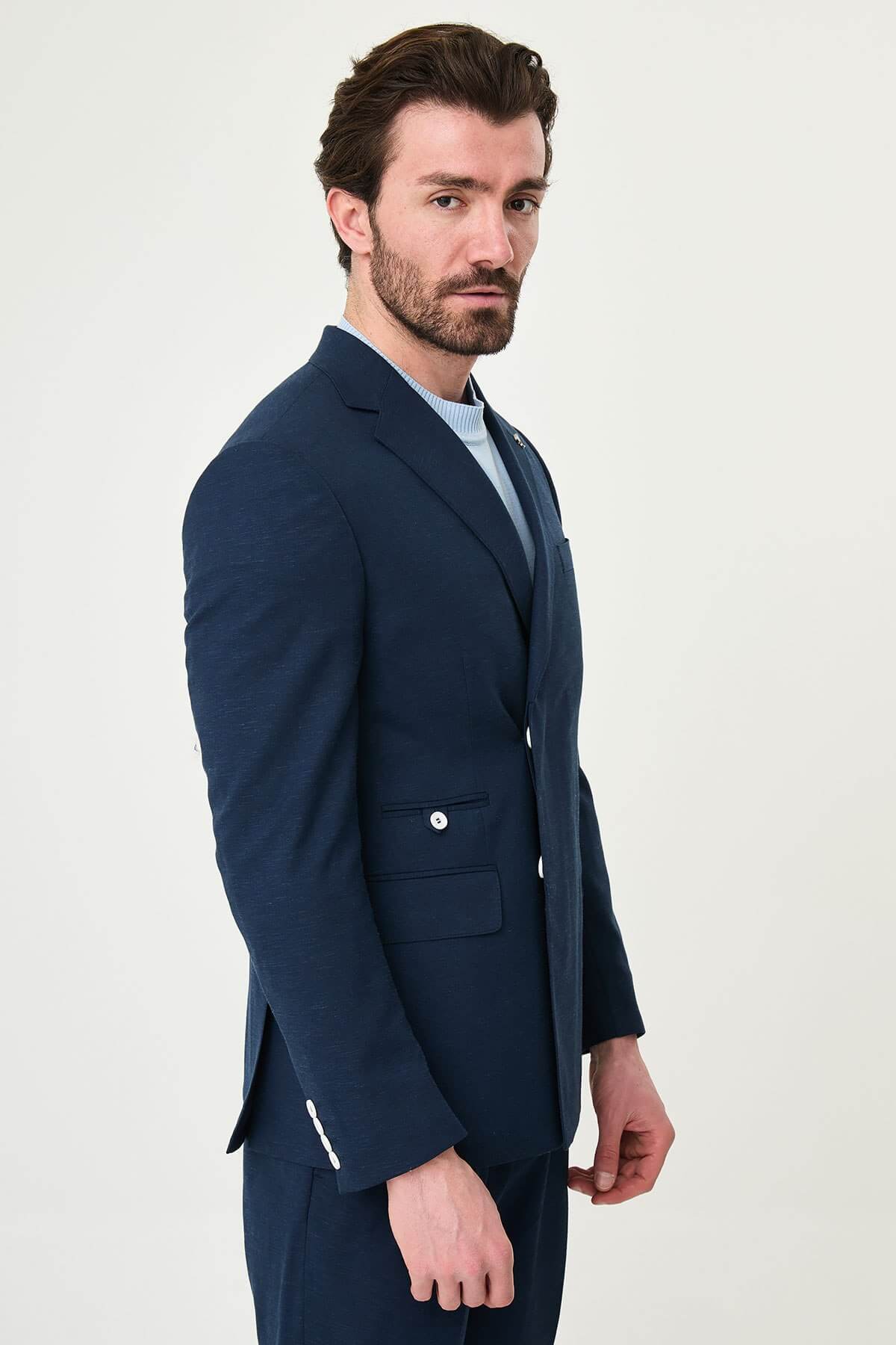 man wearing a Men’s Navy Blue Slim-fit Summer Suit, standing in a relaxed pose, showing the tailored double-breasted jacket and matching trousers.