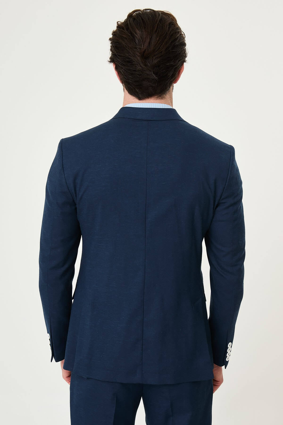 man wearing a Men’s Navy Blue Slim-fit Summer Suit, standing in a relaxed pose, showing the tailored double-breasted jacket and matching trousers.