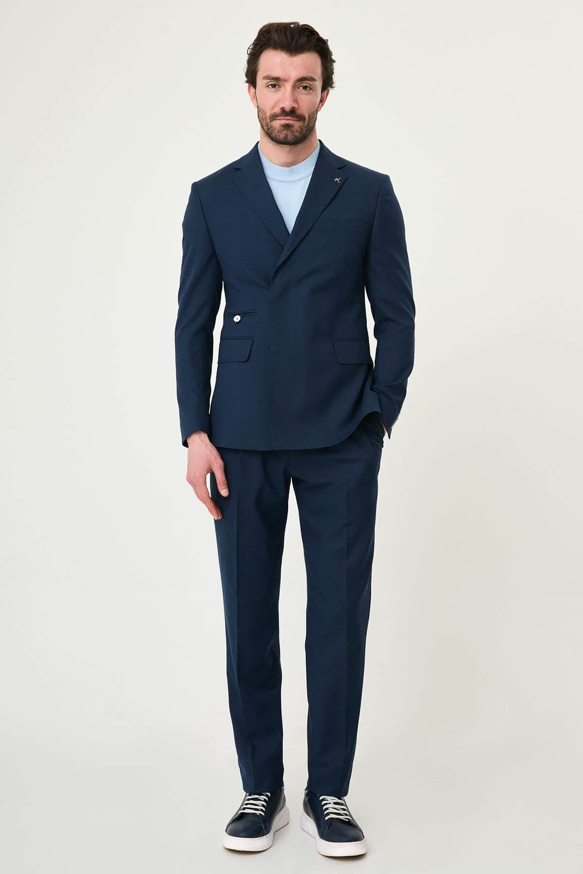 man wearing a Men’s Navy Blue Slim-fit Summer Suit, standing in a relaxed pose, showing the tailored double-breasted jacket and matching trousers.