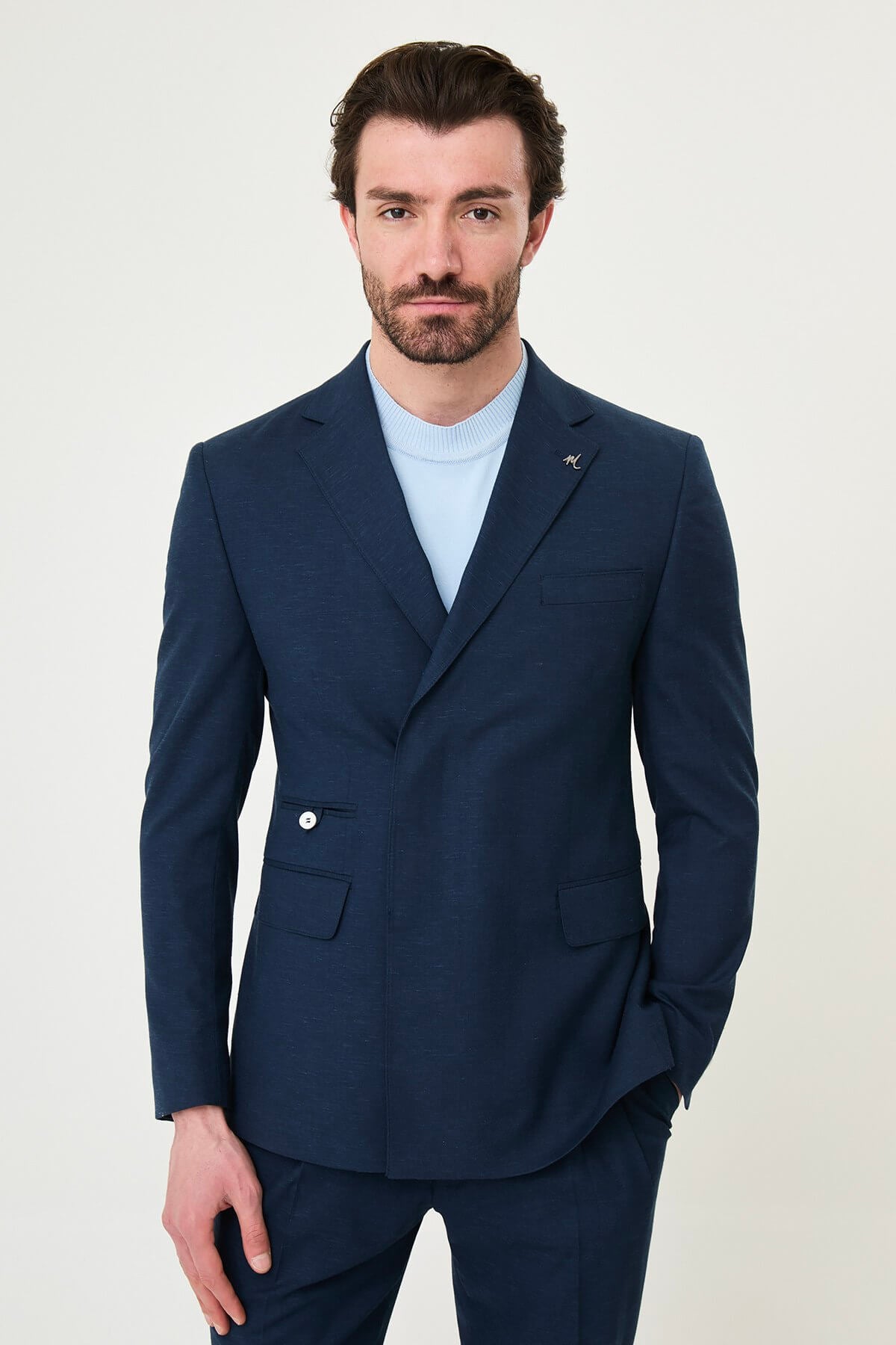 man wearing a Men’s Navy Blue Slim-fit Summer Suit, standing in a relaxed pose, showing the tailored double-breasted jacket and matching trousers.