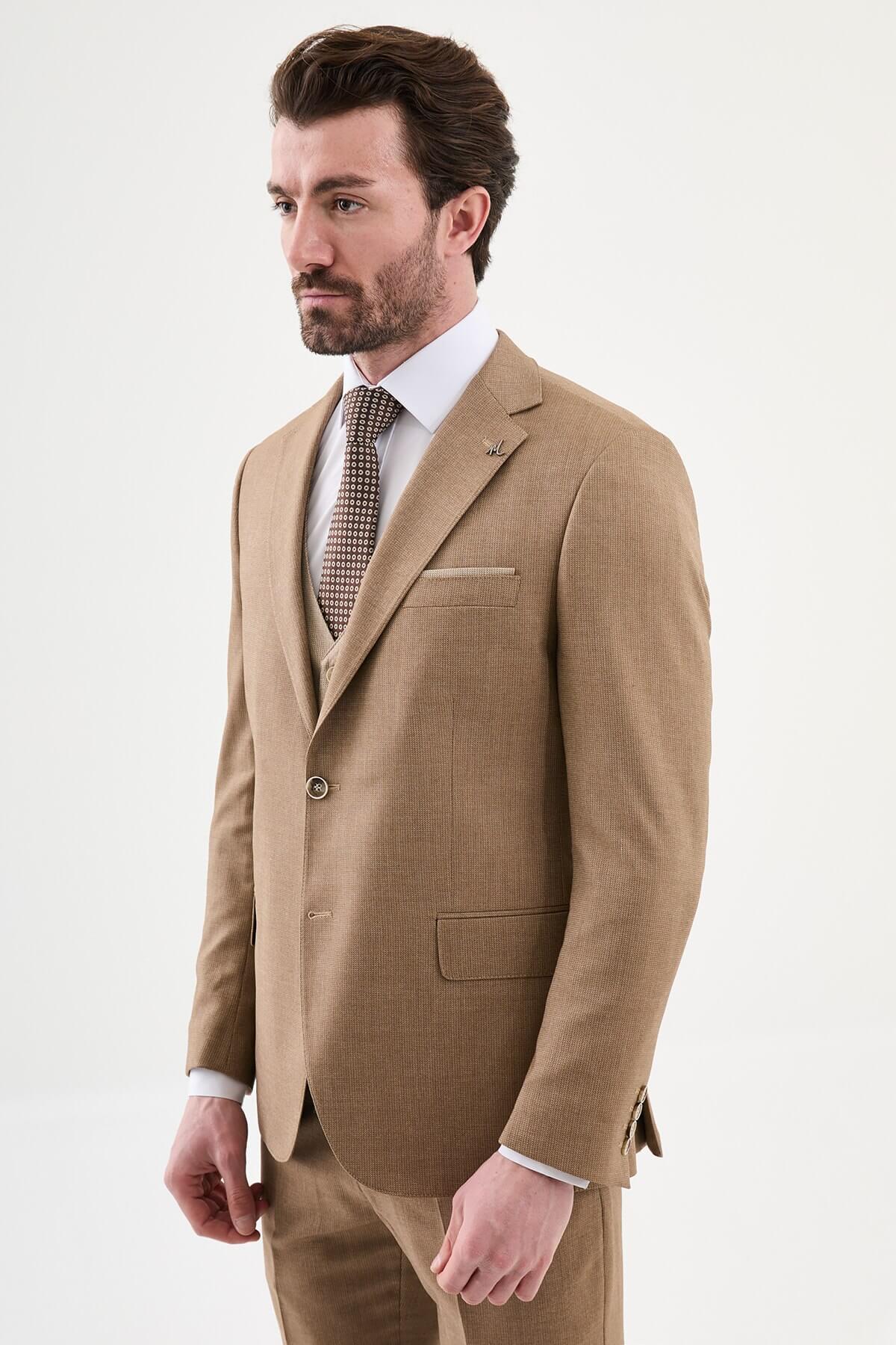 Model wearing a camel slim-fit three-piece suit with a white dress shirt, brown patterned tie, matching waistcoat, tailored trousers, and dark brown leather Derby shoes.
