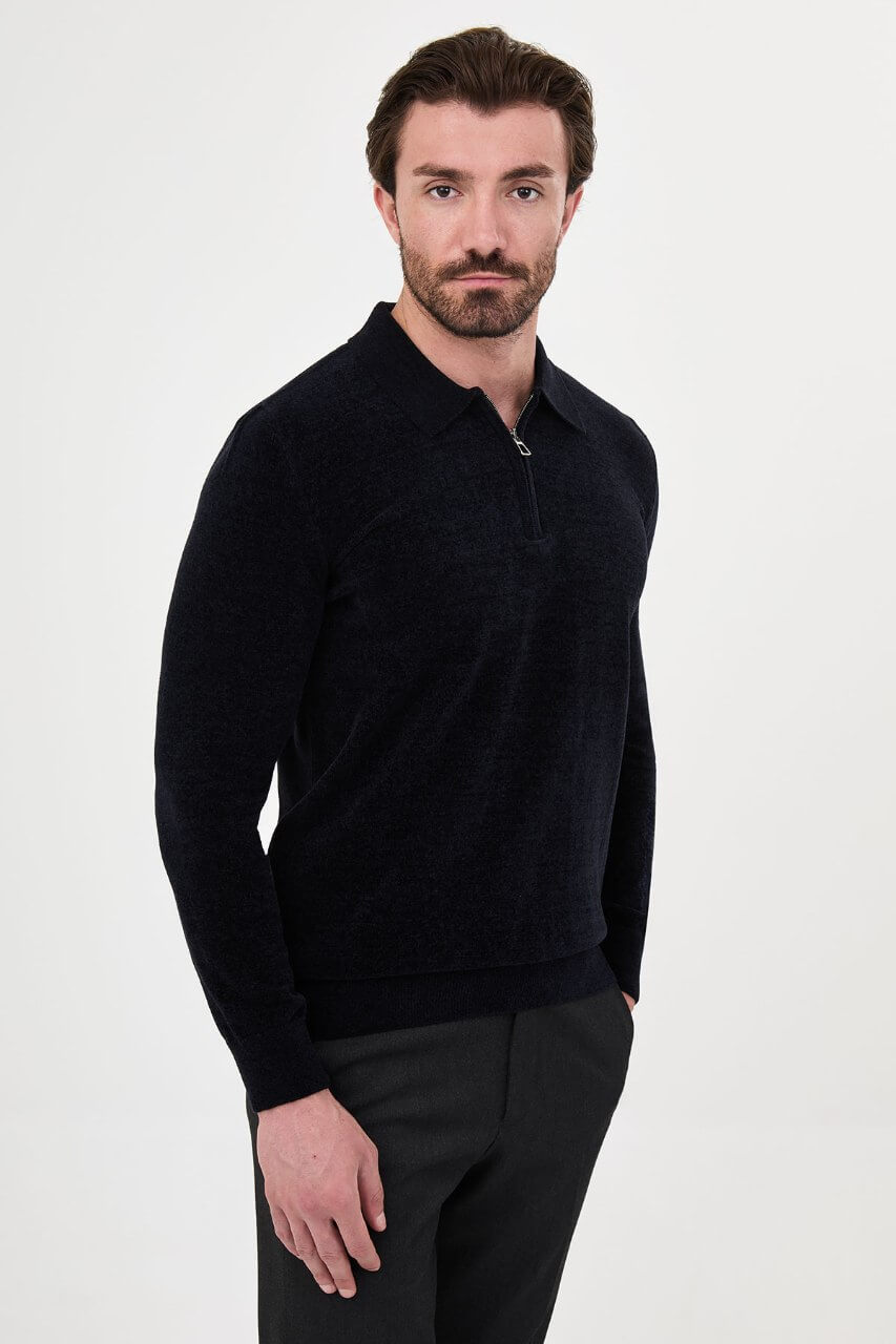 Men’s navy blue polo neck knit sweater with zip collar detail styled with dark trousers for a refined fall winter smart-casual outfit.