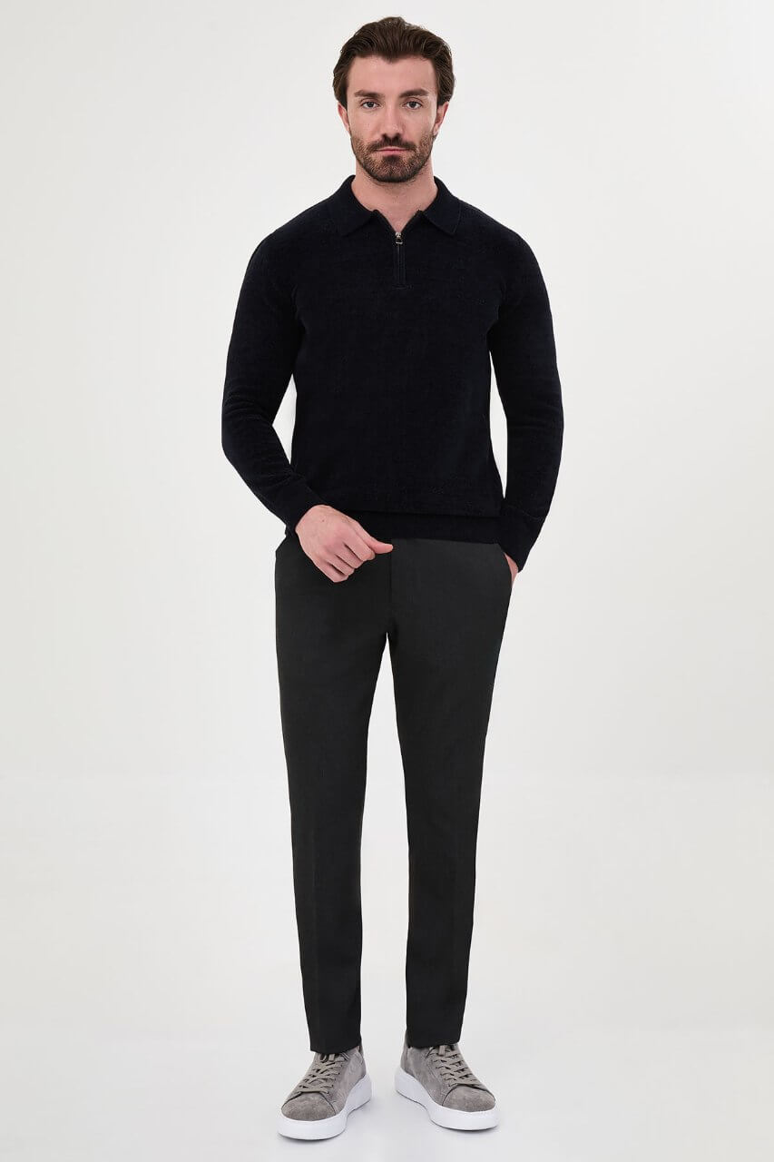 Men’s navy blue polo neck knit sweater with zip collar detail styled with dark trousers for a refined fall winter smart-casual outfit.