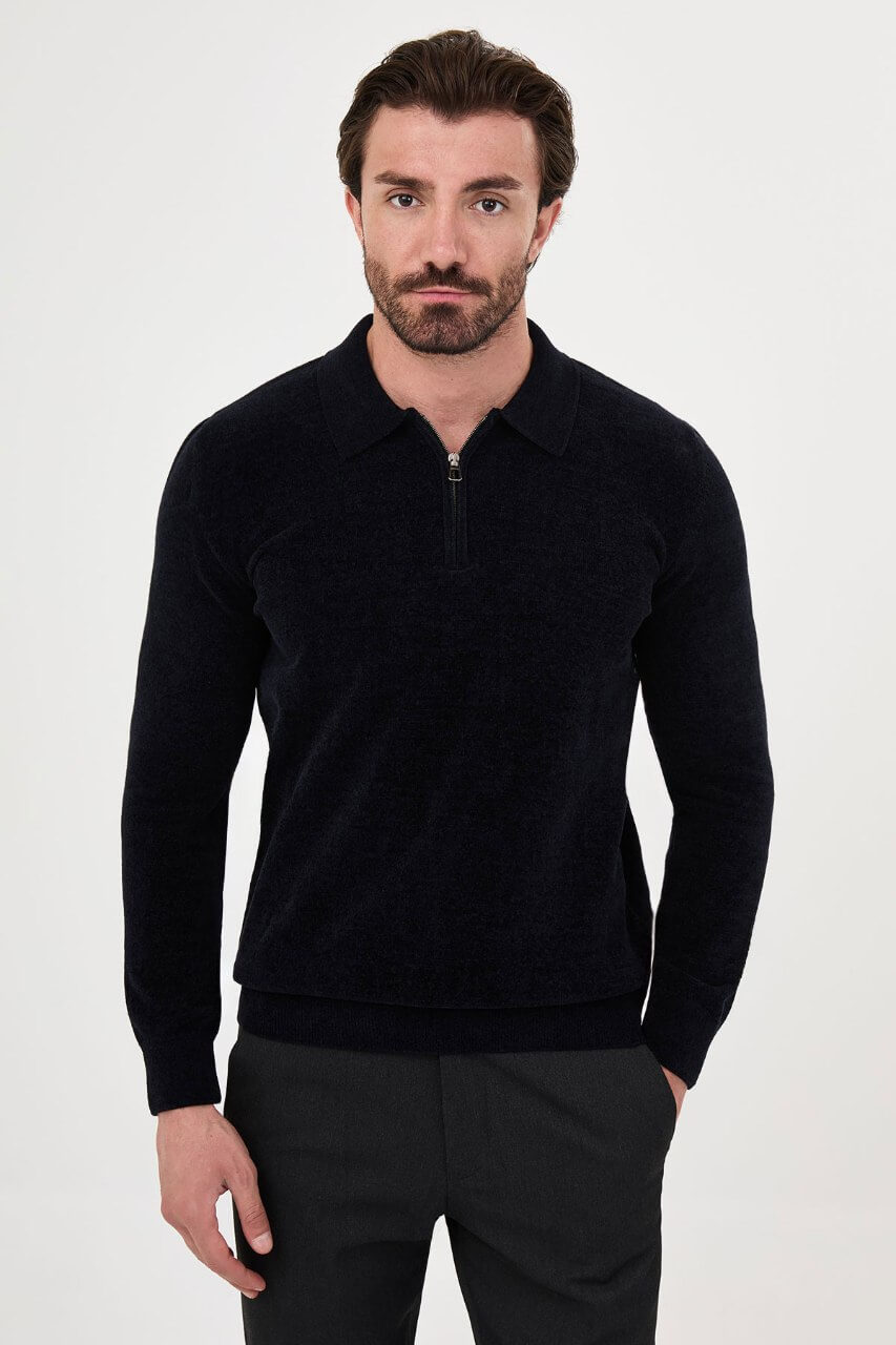 Men’s navy blue polo neck knit sweater with zip collar detail styled with dark trousers for a refined fall winter smart-casual outfit.