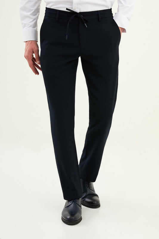 Men wearing navy blue slim-fit drawstring trousers with elastic waistband, tapered slim fit, styled with dress shoes and sneakers for versatile summer menswear.