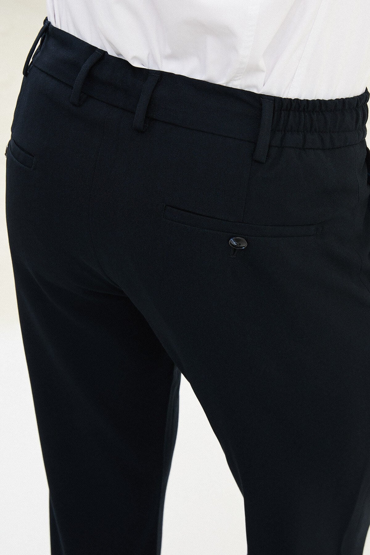 Men wearing navy blue slim-fit drawstring trousers with elastic waistband, tapered slim fit, styled with dress shoes and sneakers for versatile summer menswear.