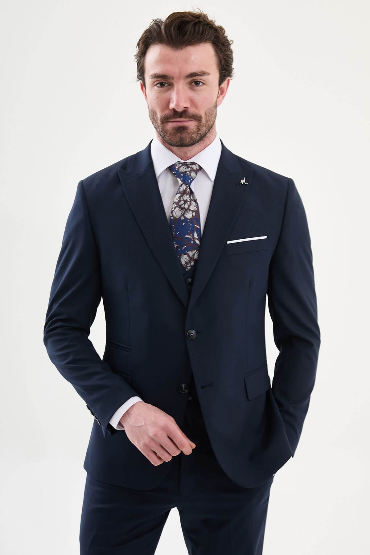 man wearing a navy blue slim-fit three-piece suit, including blazer, vest, and trousers, styled with a white shirt and tie, suitable for summer weddings and business events.