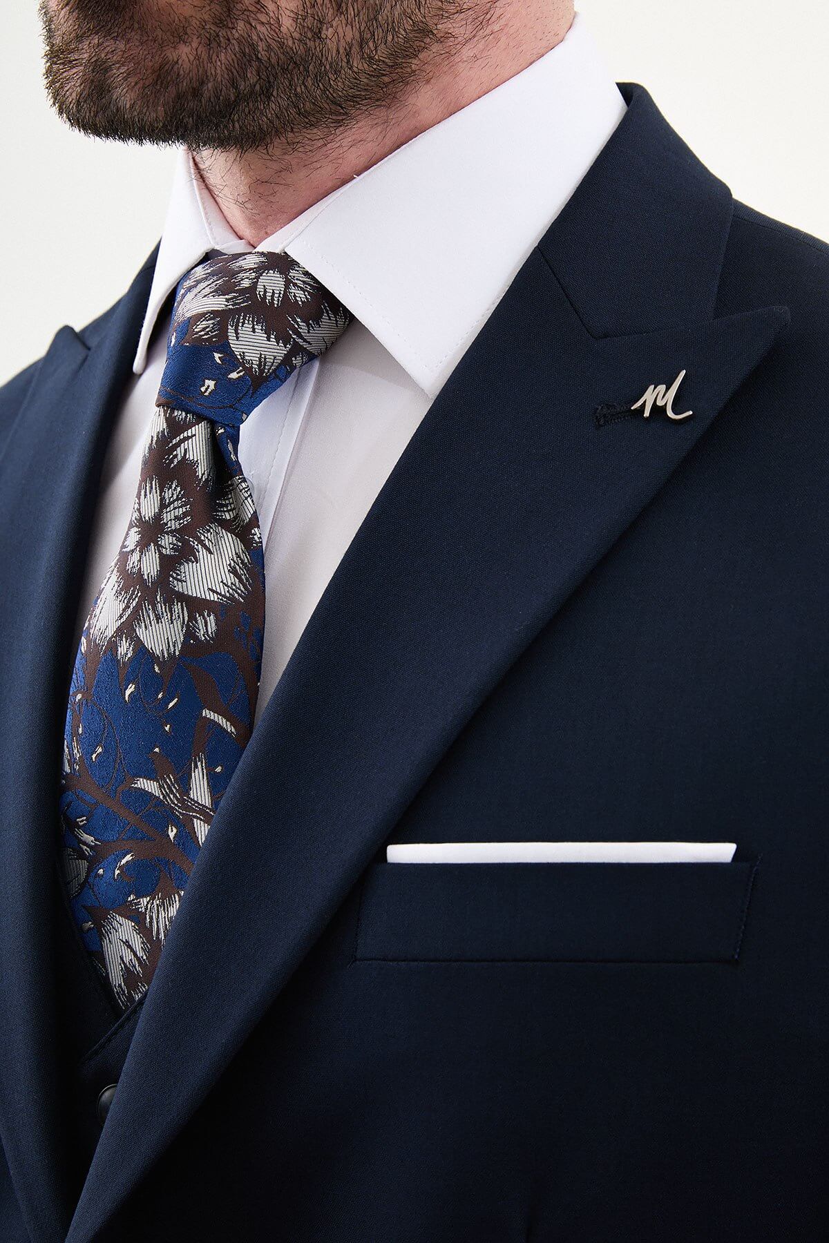 man wearing a navy blue slim-fit three-piece suit, including blazer, vest, and trousers, styled with a white shirt and tie, suitable for summer weddings and business events.