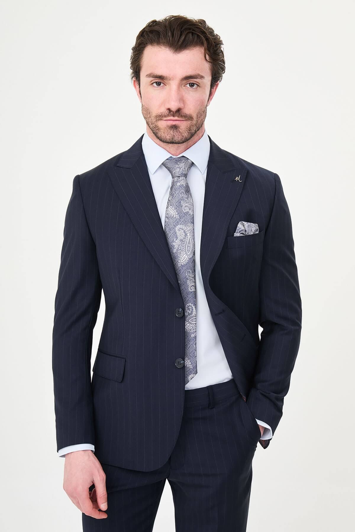 Man wearing a navy blue slim fit premium wool suit with wide collar, styled with matching trousers and a patterned tie