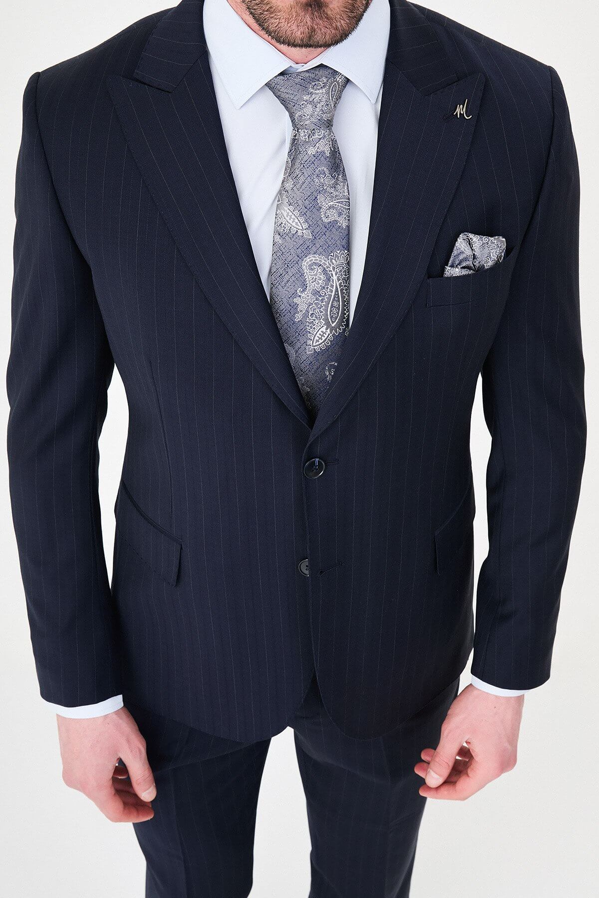 Man wearing a navy blue slim fit premium wool suit with wide collar, styled with matching trousers and a patterned tie
