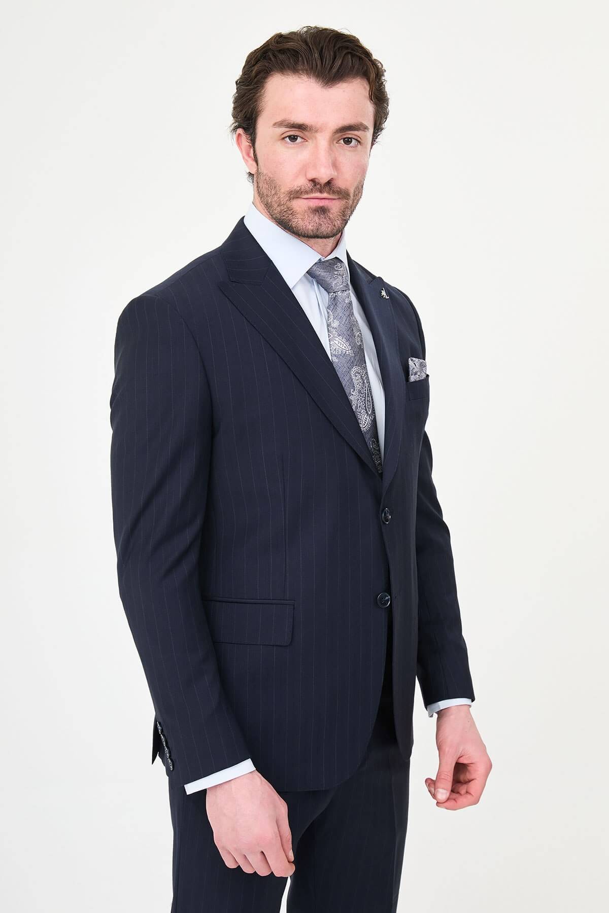 Man wearing a navy blue slim fit premium wool suit with wide collar, styled with matching trousers and a patterned tie